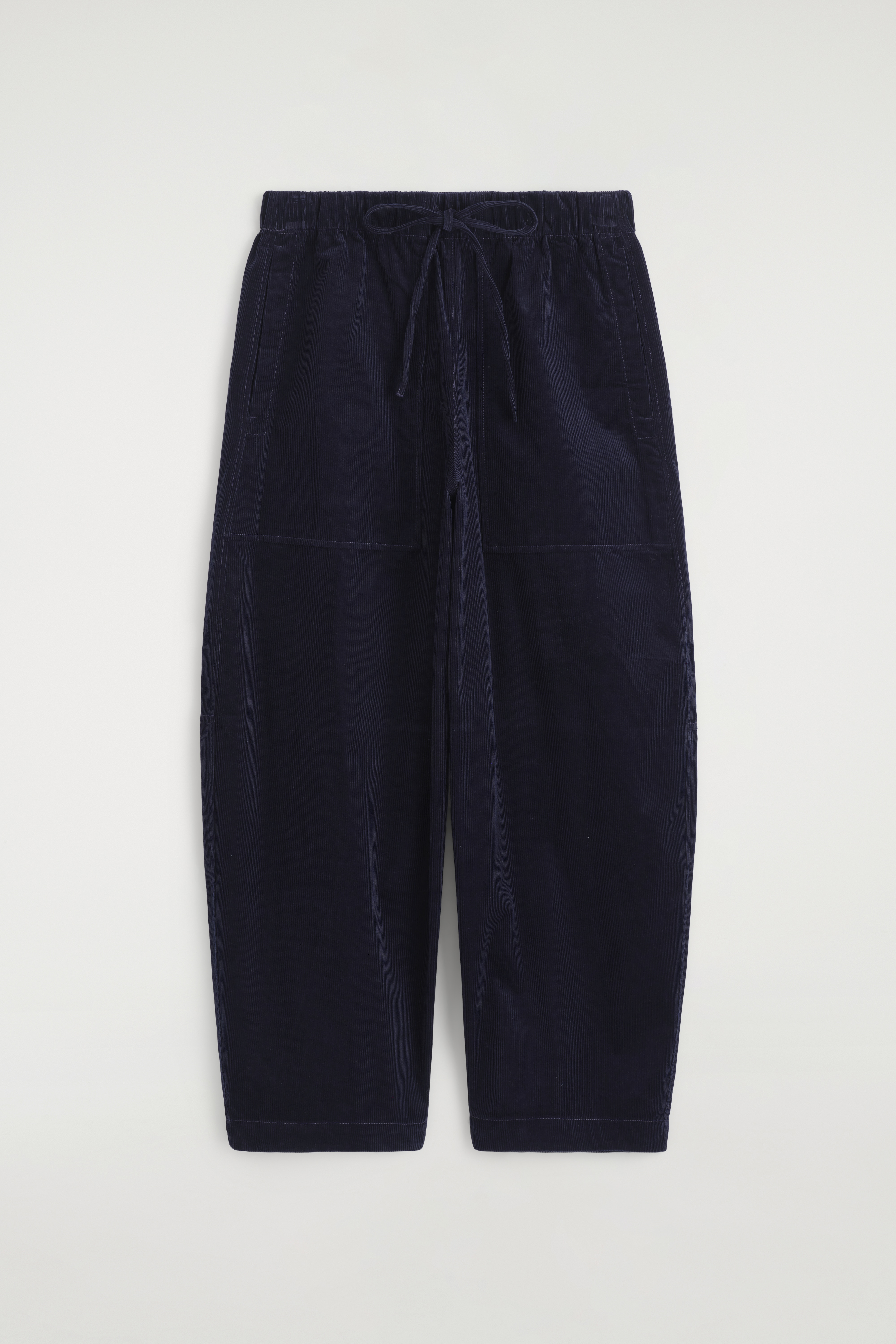 ÐанÑалони Ñип barrel-leg Ð¾Ñ ÑипÑено кадиÑе в ÑÑмноÑинÑо navy blue Ñа ноÑени Ð¾Ñ Ð¼Ð¾Ð´ÐµÐ»Ð°, Ñ ÑиÑока, извиÑа ÑилÑеÑна Ð»Ð¸Ð½Ð¸Ñ Ð¸ пÑедни накладни джобове. ÐанÑалониÑе Ñа комбиниÑани Ñ ÑÑмна поло Ñиза Ñ Ð´ÑлÑг ÑÑкав, Ñив плеÑен пÑловеÑ, вÑÑзан около ÑалиÑÑа, и ÑеÑни боÑи Ñ Ð¾ÑÑÑÑ Ð²ÑÑÑ
.