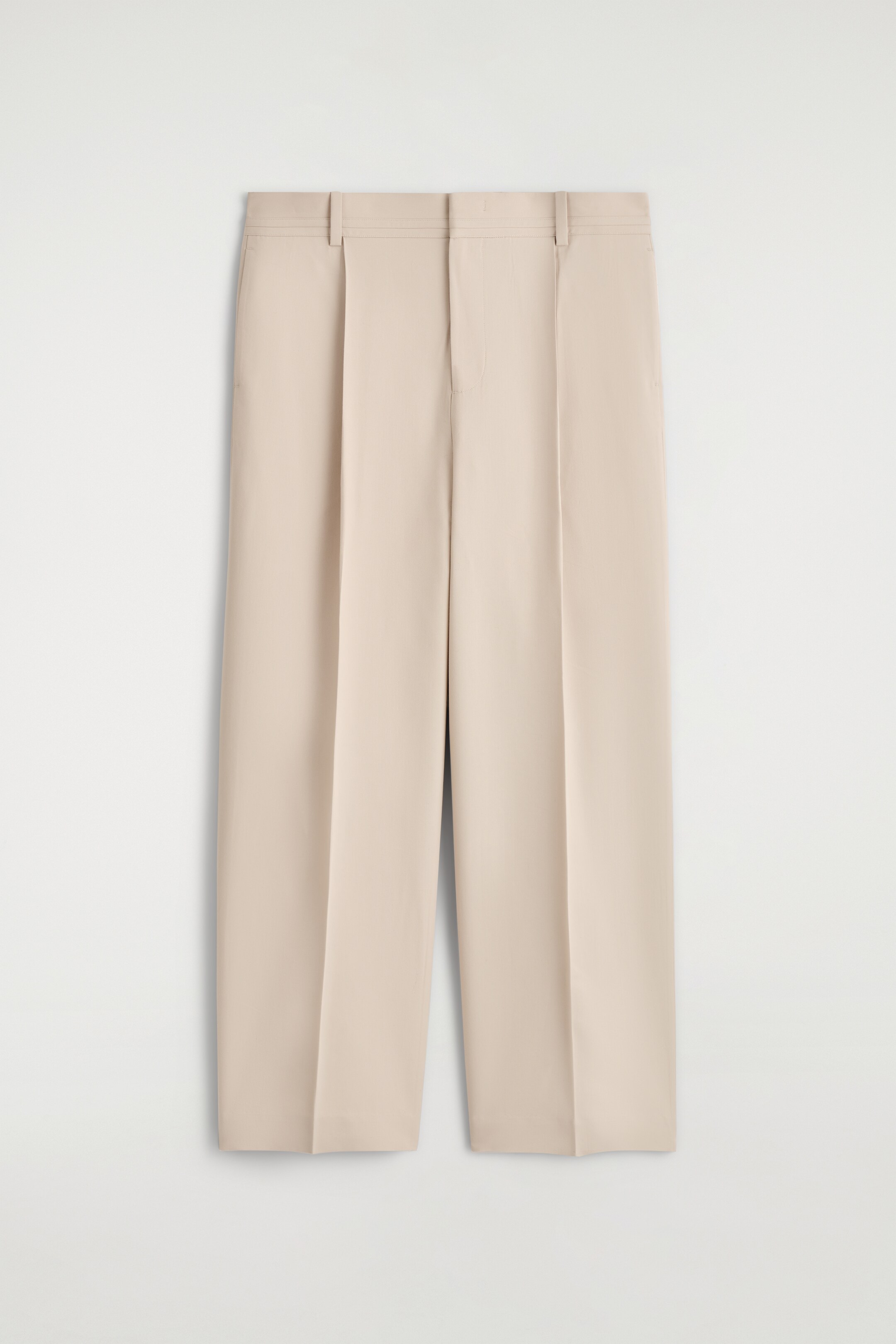 Agrandir l'image: Une paire de pantalons beige clair présente sa vue de FACE, posée à plat. Elle est dotée d'une ceinture plate avec des passants de ceinture, de doubles plis sur chaque jambe avant, et de plis marqués descendant jusqu'aux ourlets larges et raccourcis.