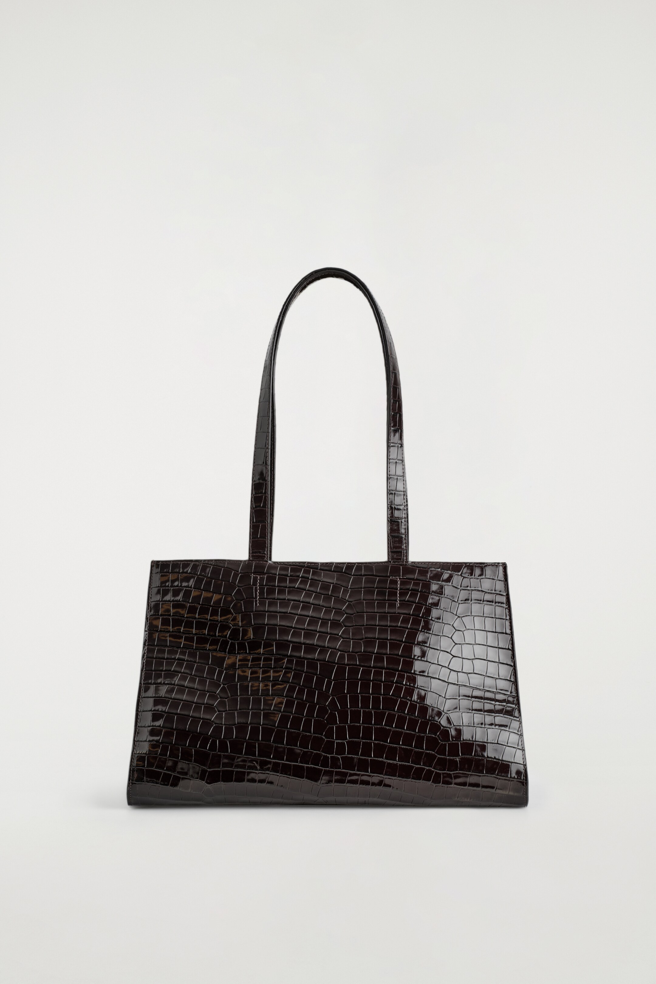 Agrandir l'image: Un sac cabas en cuir embossé croco d'un brun foncé et poli est présenté de face, arborant une silhouette est-ouest et deux longues anses pour l'épaule.