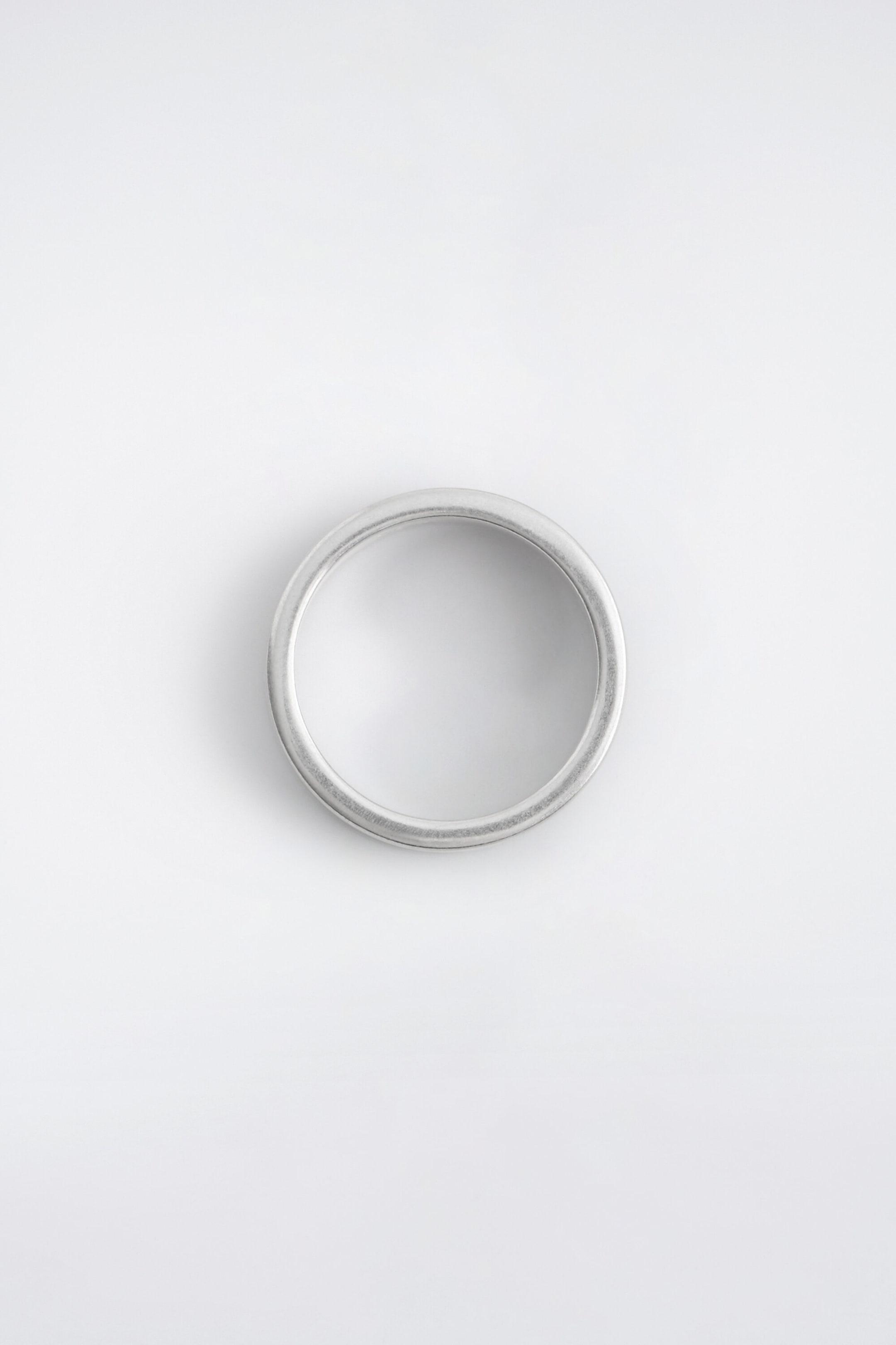A silver-plated brass ring is displayed with a clean-lined circular band and a matte, brushed finish, shown from a top-down perspective. A silver-plated brass ring is displayed with a clean-lined circular band and a matte, brushed finish, shown from a top-down perspective.