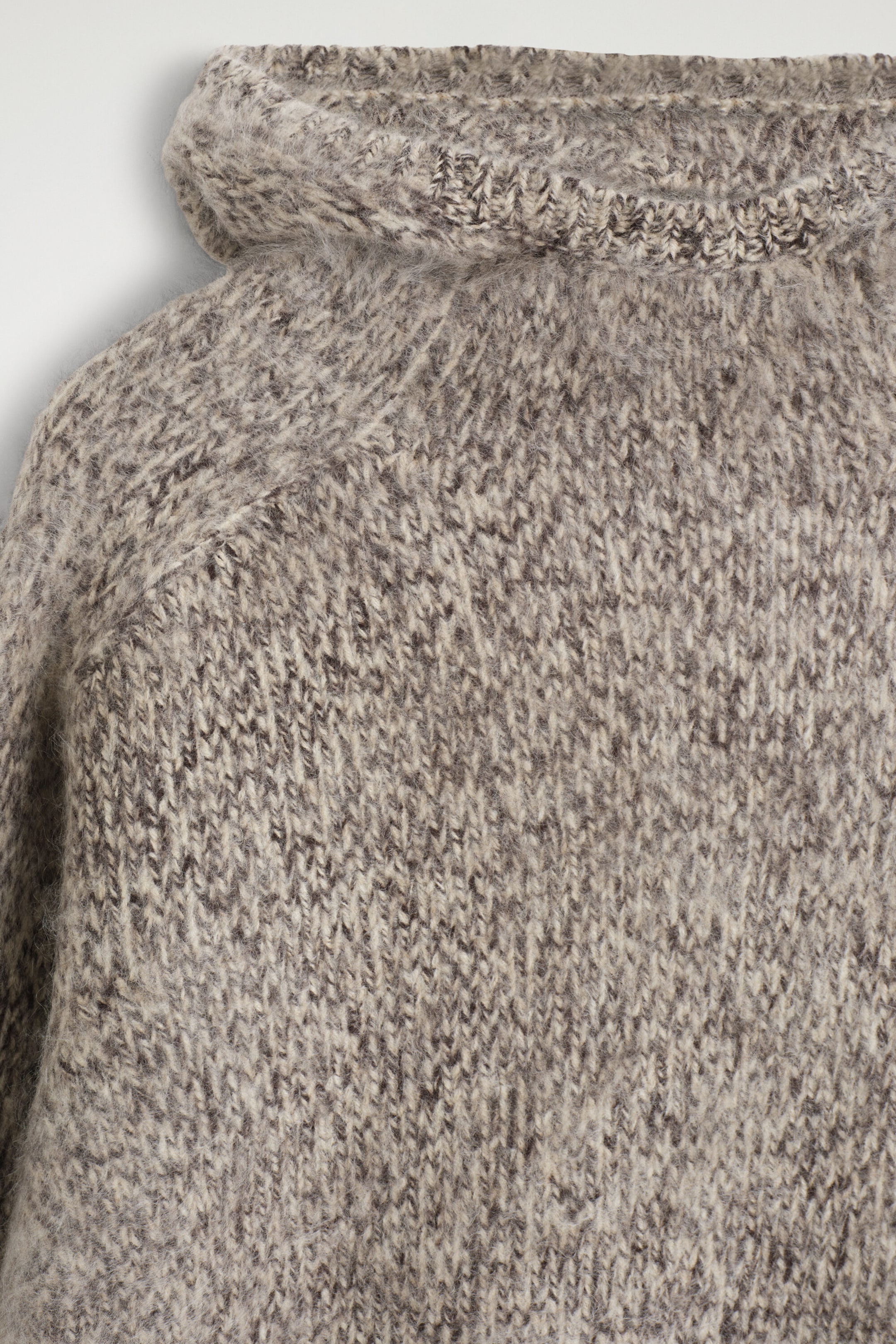 A close-up front view showcases the chunky brushed-cashmere hoodie, featuring a thick, marled knit in shades of grey and beige. The fuzzy, brushed texture highlights the raglan sleeve construction and the ribbed trim of the hood. A close-up front view showcases the chunky brushed-cashmere hoodie, featuring a thick, marled knit in shades of grey and beige. The fuzzy, brushed texture highlights the raglan sleeve construction and the ribbed trim of the hood.
