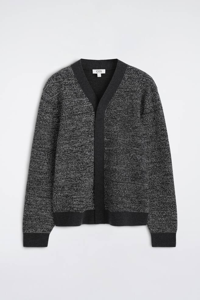 This knit cardigan is shown from the front, featuring a textured grey and black marled pattern. It showcases a deep V-neckline with a solid charcoal grey trim that continues down the open front, complemented by matching ribbed cuffs and hem. - 1