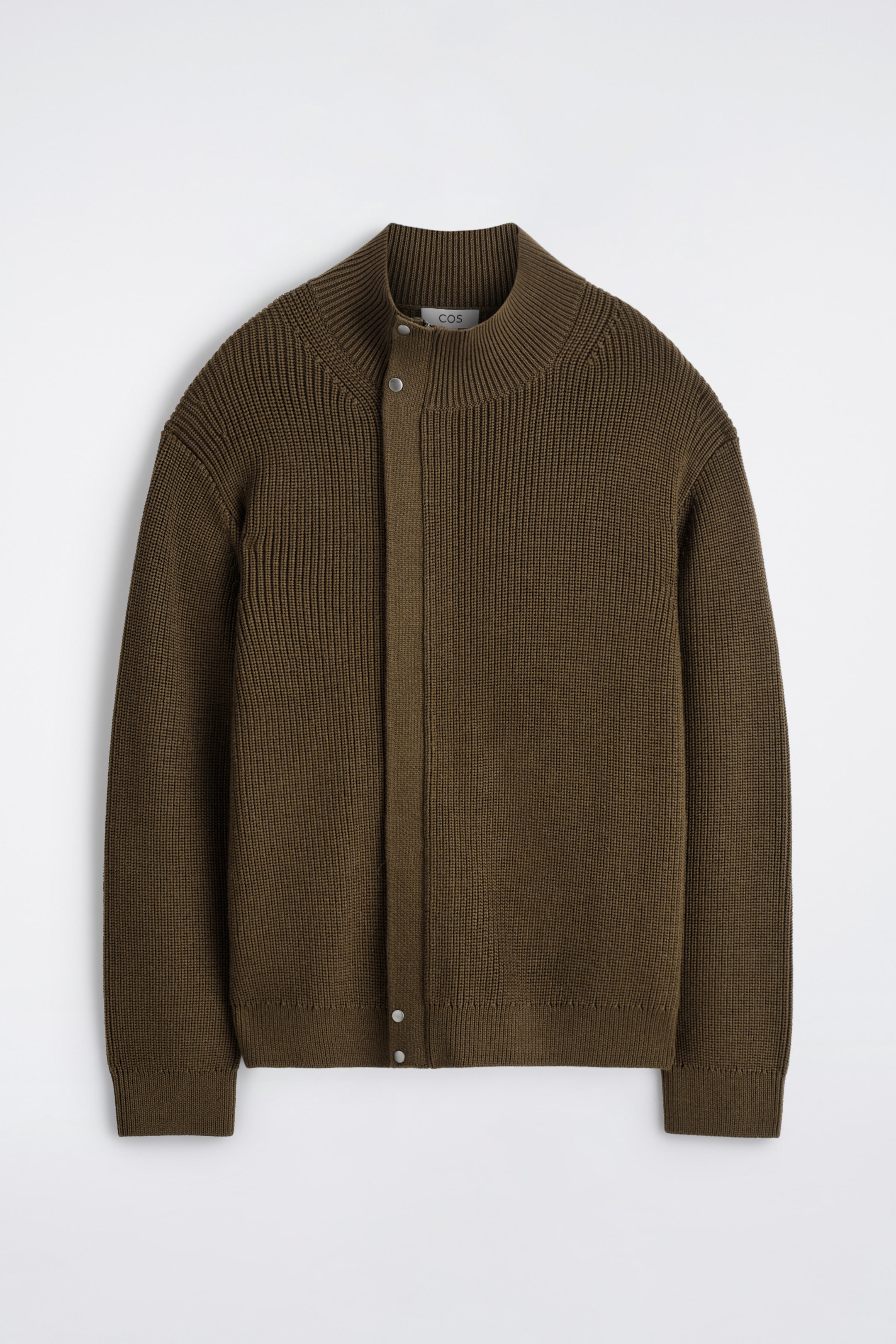 Agrandir l'image: Une veste de ton chocolat est présentée de face, avec une texture en maille côtelée sur tout le corps et des manches longues. Elle possède un col montant côtelé et une patte de boutonnage asymétrique à l'avant, qui se ferme avec des boutons-pression visibles de couleur argentée.