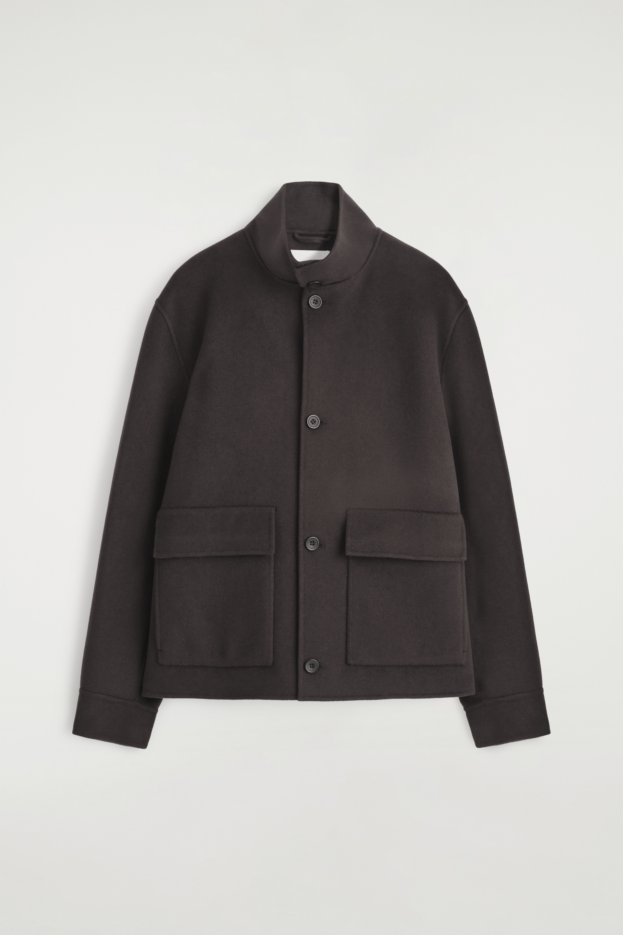 Grösseres Bild ansehen: Eine dunkelbraune Jacke wird von vorne präsentiert, mit einem hohen Trichterkragen und einem zentralen Knopfverschluss. Sie ist mit zwei großen, rechteckigen Klappentaschen an der unteren Vorderseite und breiten, geraden Ärmeln gestaltet.