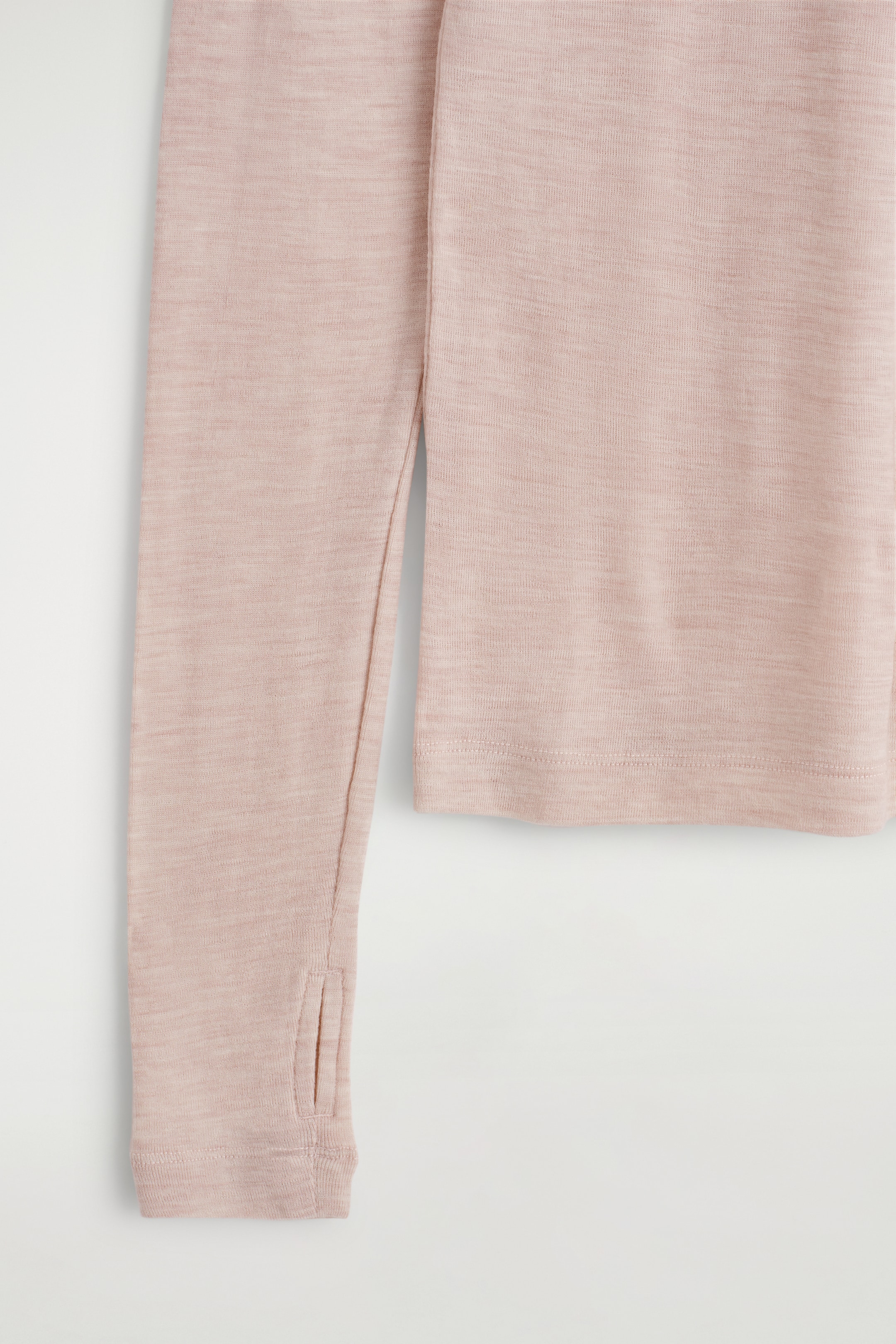 View larger image: A light pink, fine knit long-sleeved top is being displayed, showing its sleeve with a thumbhole cuff and a flat bottom hem.