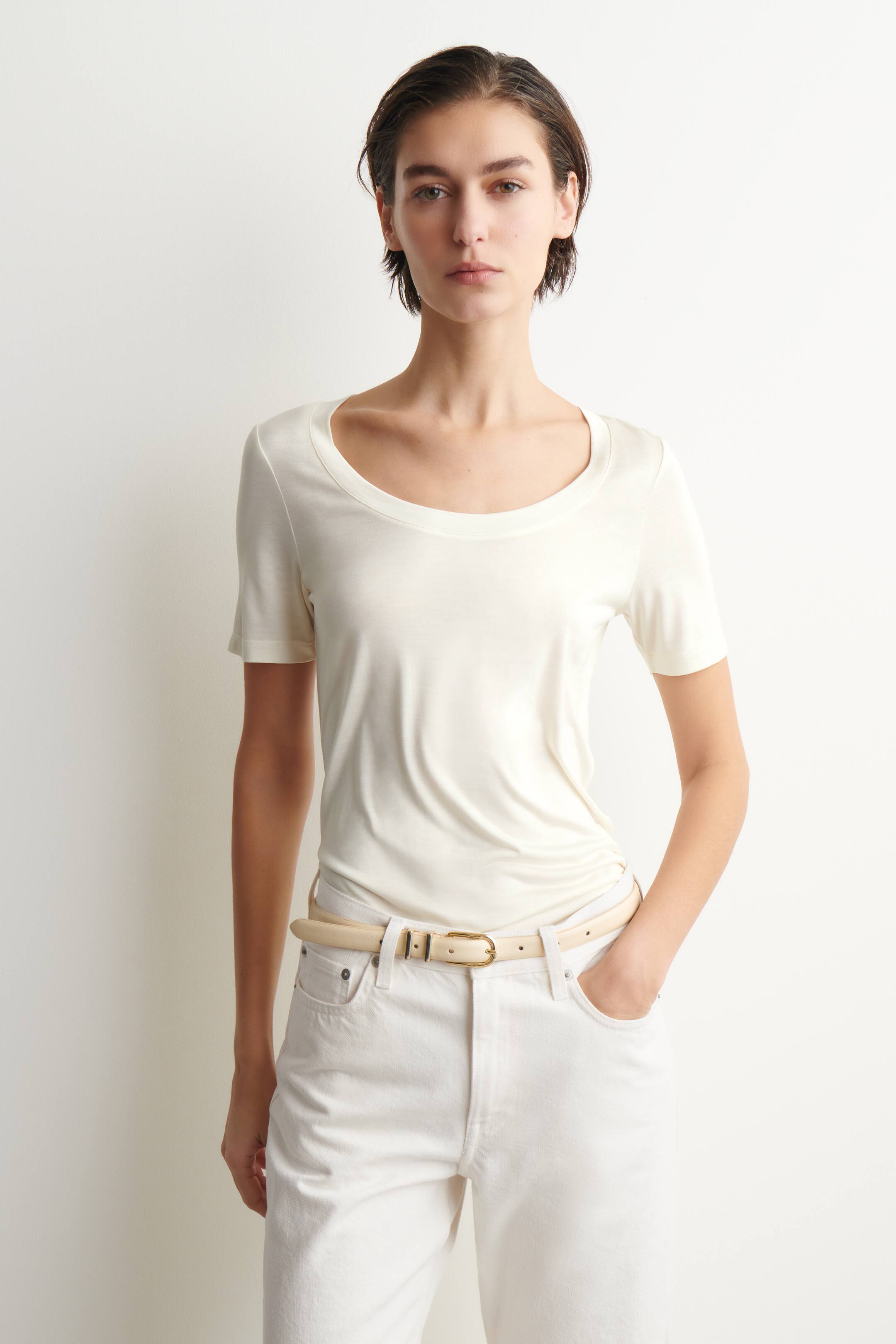 Ver imagen más grande: Una camiseta blanca roto presenta un amplio escote redondo y mangas cortas, luciendo ajustada y de frente. Su tejido ligero cae suavemente y se recoge donde está metida en unos pantalones blancos.