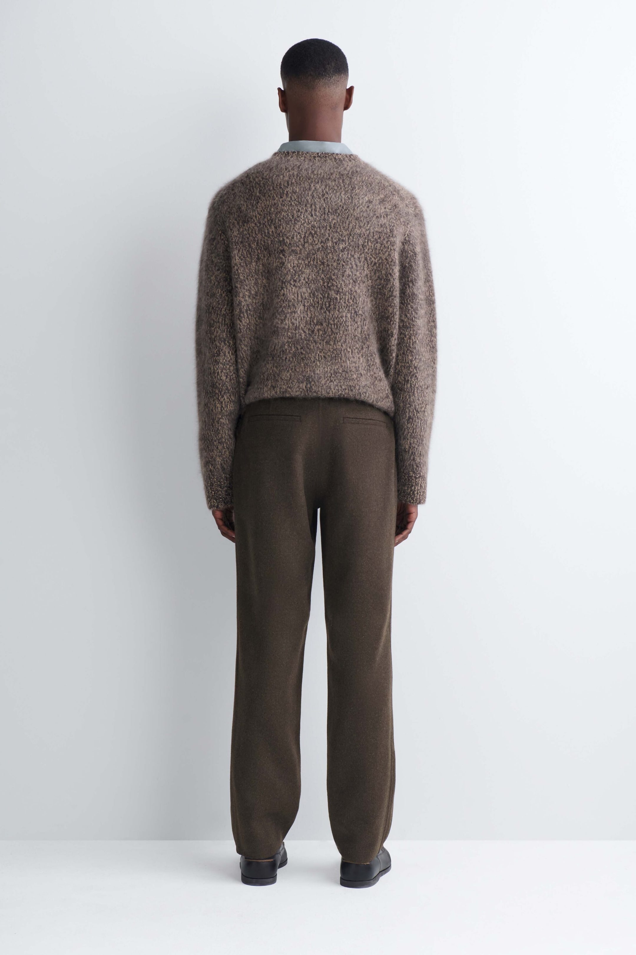 The model is wearing dark brown double-faced wool-blend straight-leg pants, shown from the back. The pants feature two back welt pockets and are styled with a textured brown sweater and black shoes. The model is wearing dark brown double-faced wool-blend straight-leg pants, shown from the back. The pants feature two back welt pockets and are styled with a textured brown sweater and black shoes.