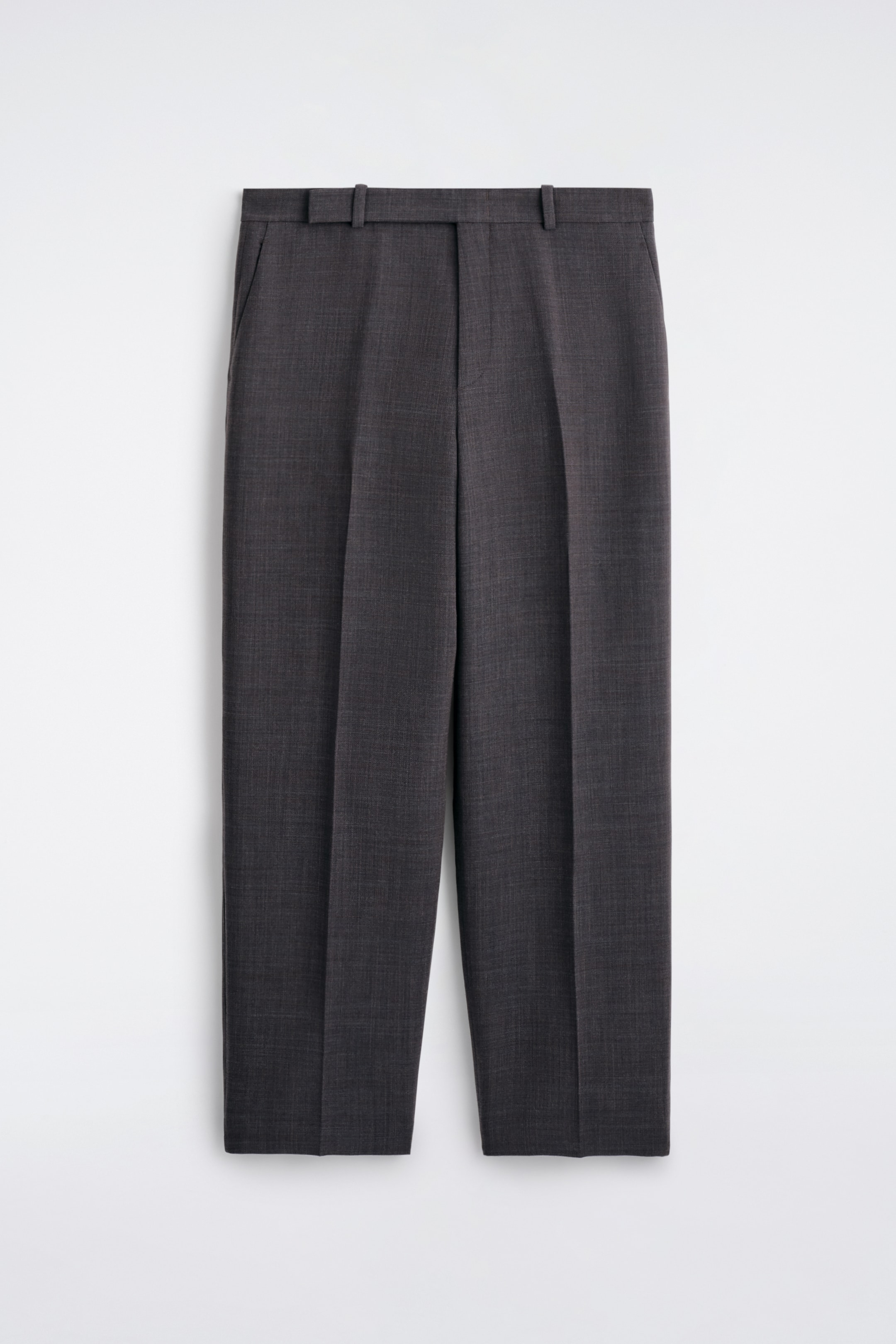 Agrandir l'image: Un pantalon gris foncé à jambes droites est présenté, face à l'avant, avec des plis verticaux marqués sur chaque jambe, une ceinture plate avec des passants et des poches latérales diagonales.