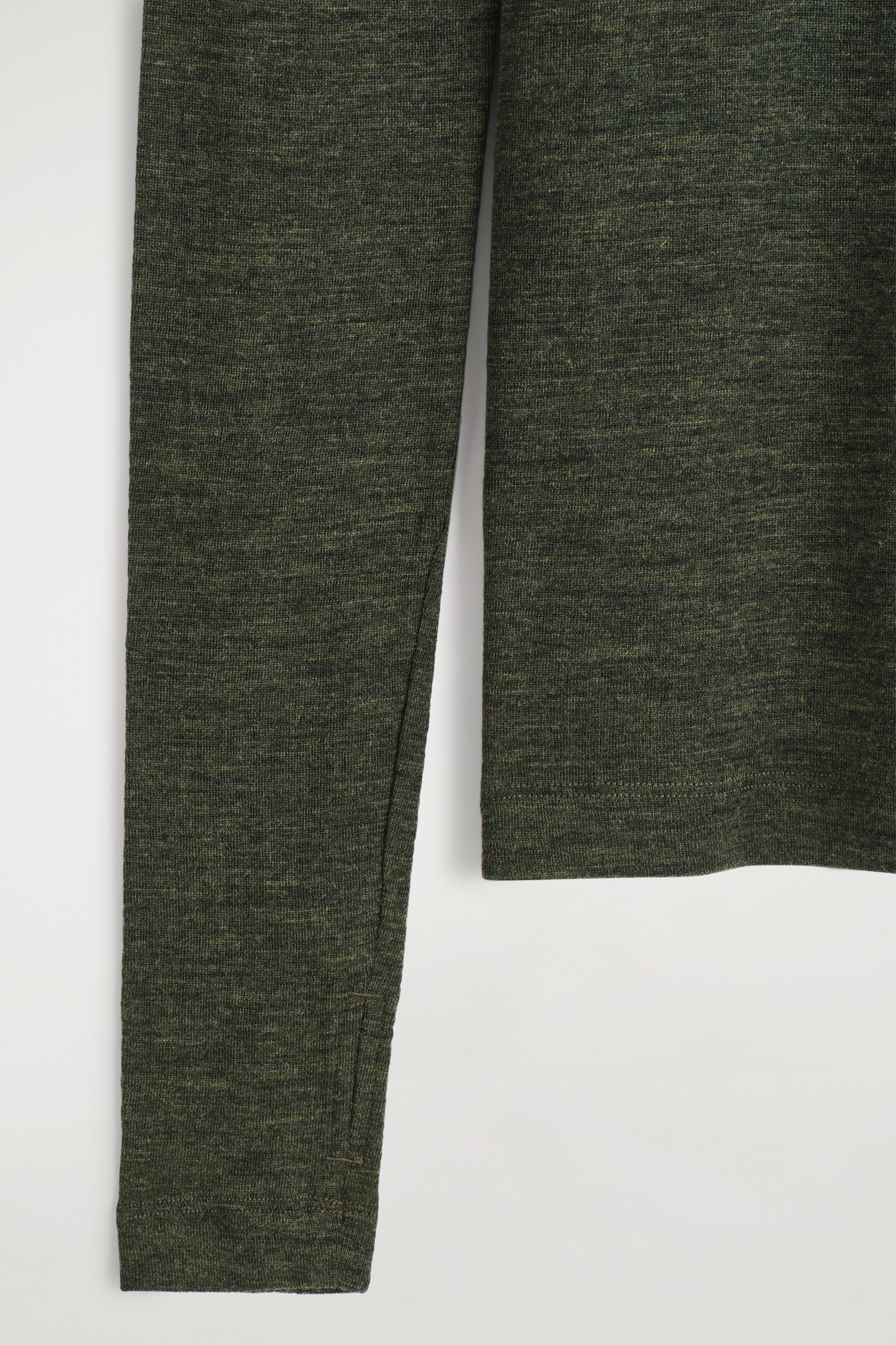 View larger image: A dark green heathered long-sleeved top is displaying its fine knit texture. A thumbhole is integrated into the left cuff, and a straight hem is finishing the garment's body.