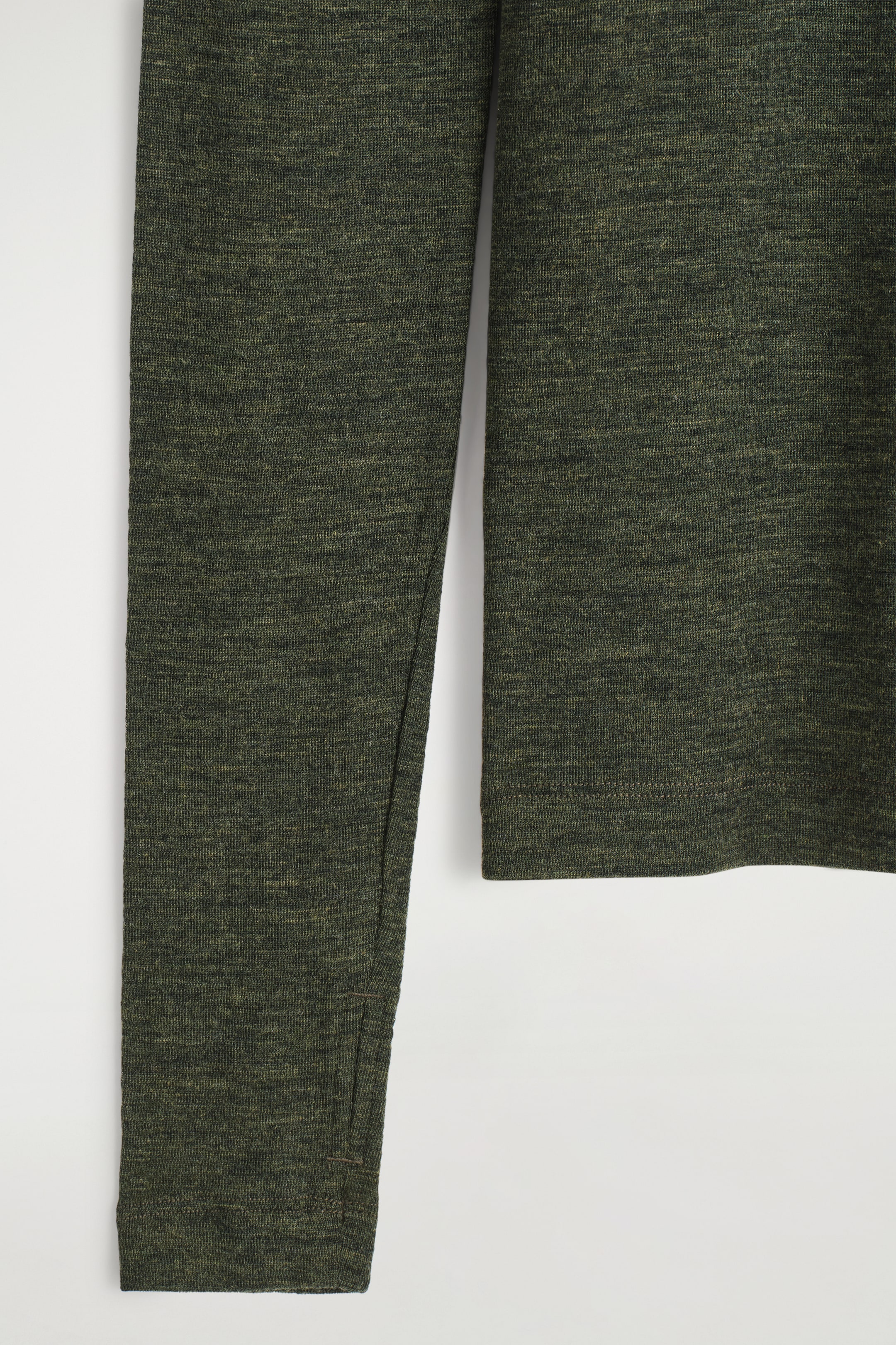 Grösseres Bild ansehen: Ein dunkelgrünes, meliertes Langarmshirt zeigt seine feine Strickstruktur. Ein Daumenloch ist in die linke Manschette integriert, und ein gerader Saum schließt den Körper des Kleidungsstücks ab.
