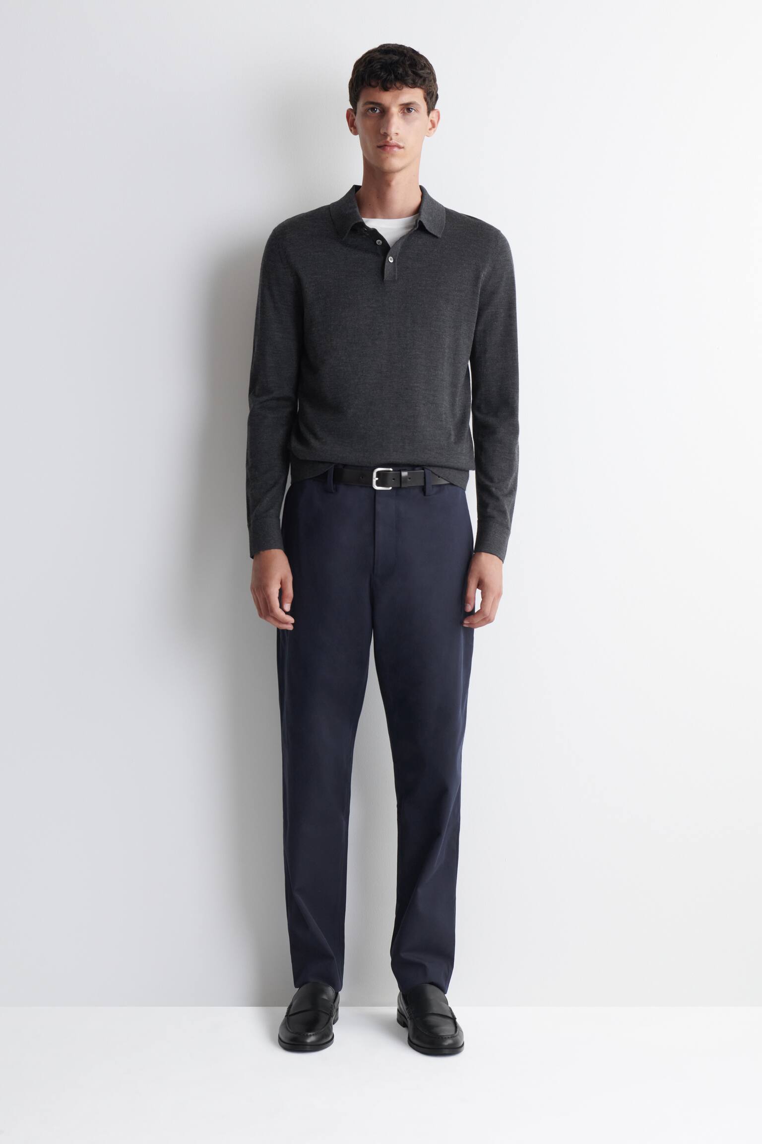 Un pantalon bleu foncé est présenté de face. Il est coupé dans une coupe slim à jambe droite et comporte des poches latérales biaisées ainsi que des passants de ceinture à la taille. - 1
