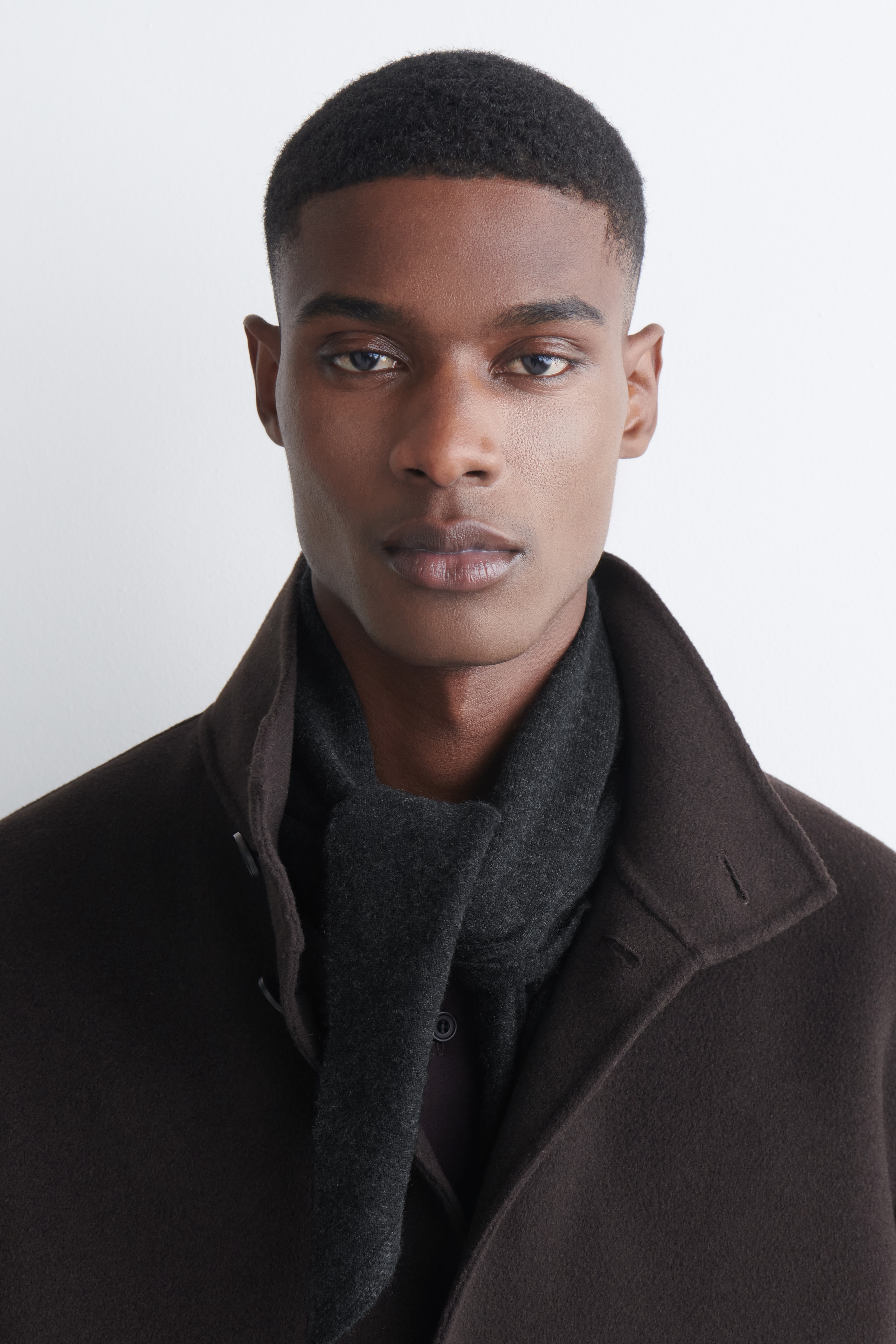 A modern dark grey triangular cashmere scarf is shown laid flat, facing FRONT. Its pointed ends cross over at the centre, creating a layered effect.