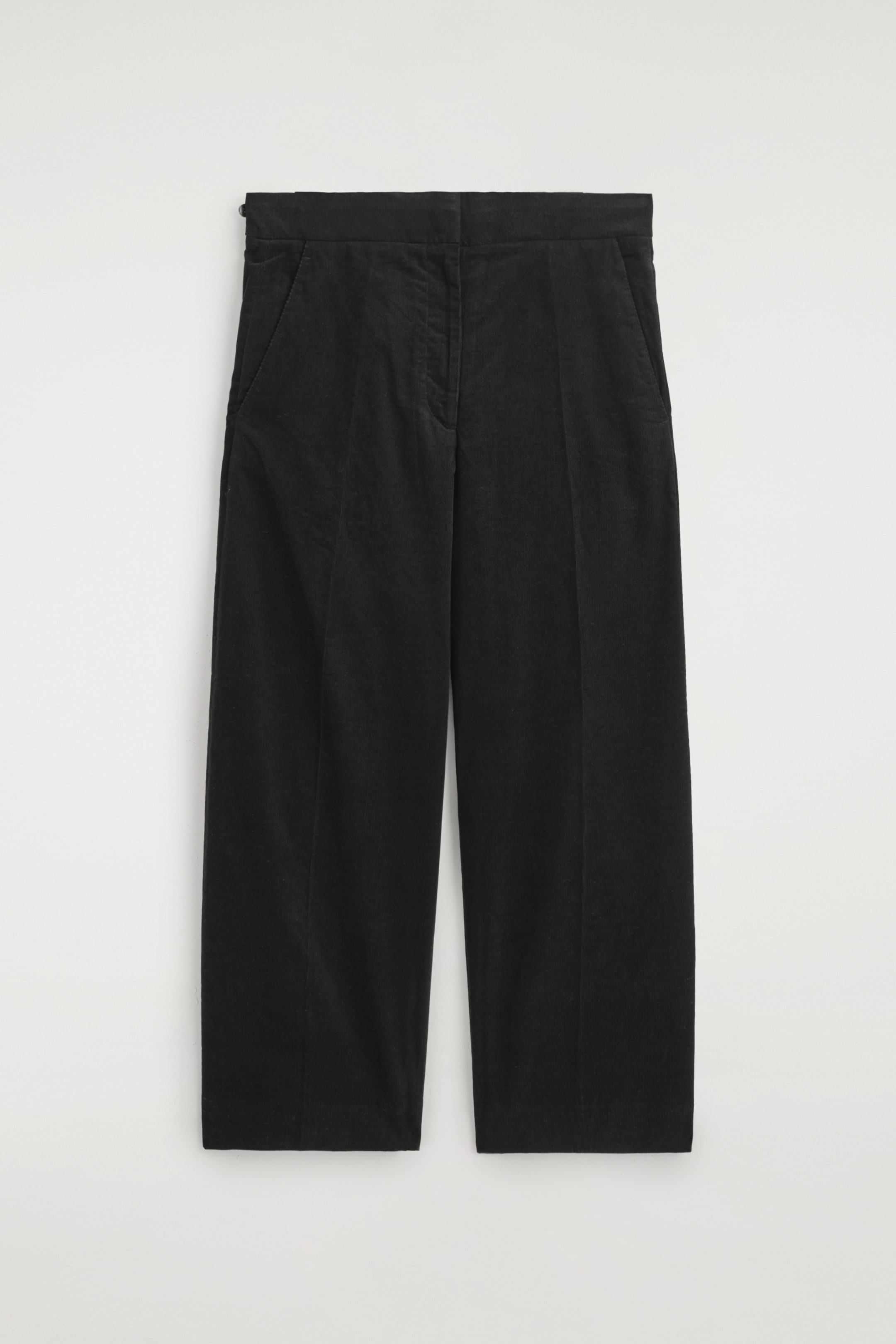 Ver imagen más grande: Pantalones de pana negros se presentan en el FRENTE, con una silueta de pierna ancha y dobladillos a la altura del tobillo. Están diseñados con bolsillos laterales en ángulo, y un pequeño cierre de cremallera es visible en el lado izquierdo de la cintura.