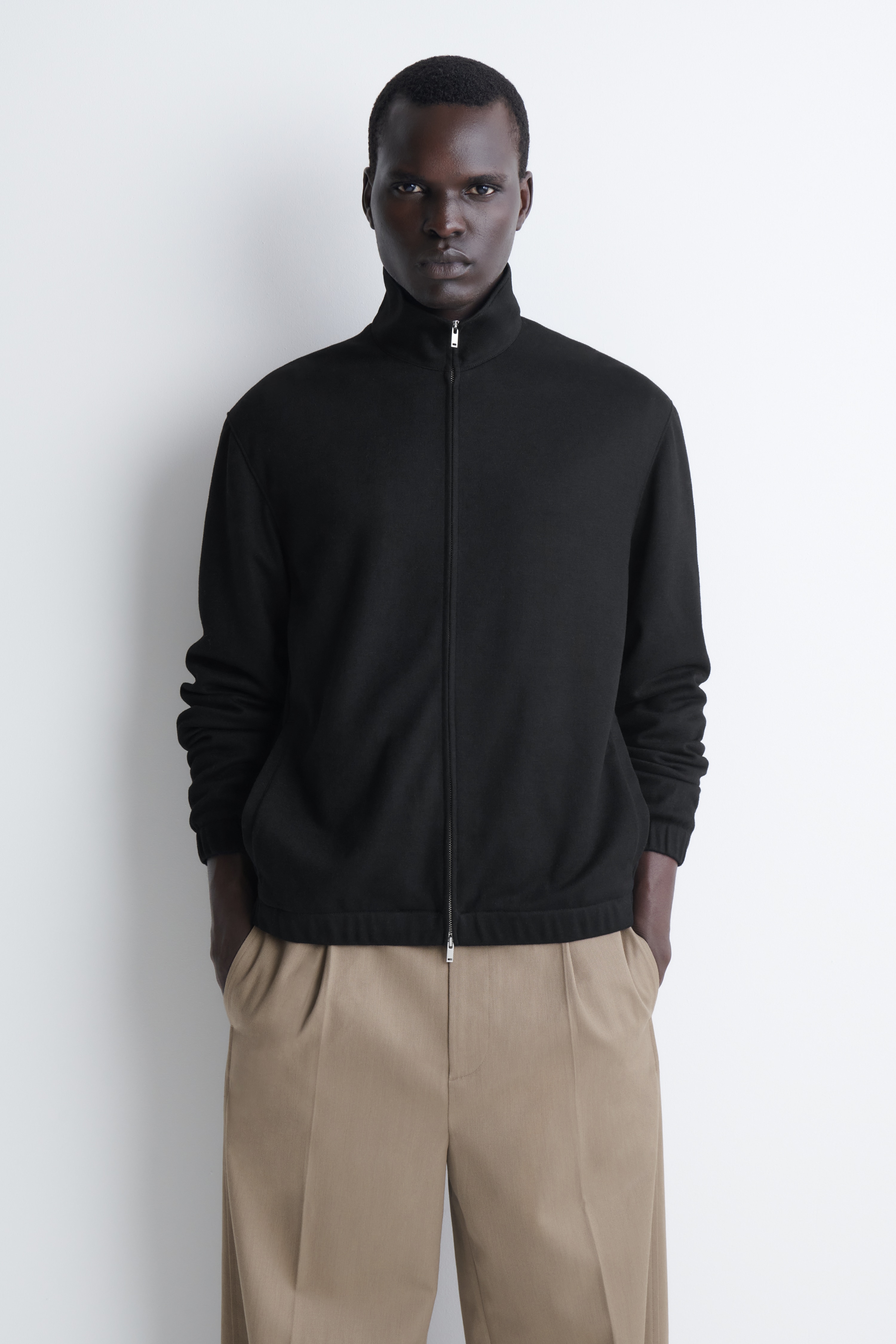 Questa giacca blouson zip-up in jersey nero con collo a funnel Ã¨ vista frontalmente e mette in risalto un colletto alto rialzato, una zip a tutta lunghezza color argento e discrete tasche laterali a filetto. Le maniche lunghe e lâorlo presentano dettagli arricciati ed elasticizzati che creano una silhouette blouson rilassata.