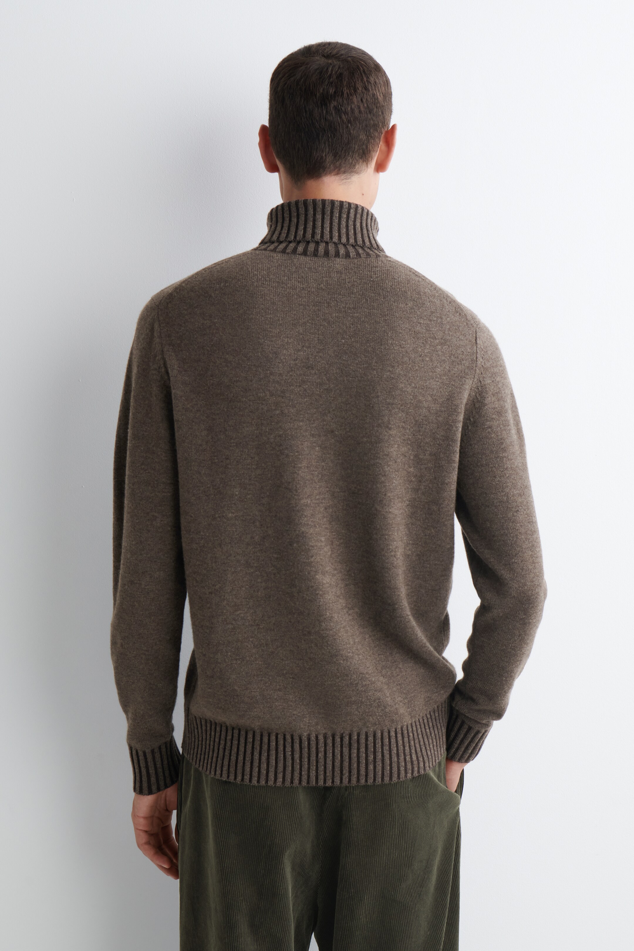 View larger image: A brown knit sweater is being shown from the back, featuring a ribbed turtleneck, ribbed cuffs, and a ribbed hem. The ribbed sections are displaying darker brown horizontal stripes.