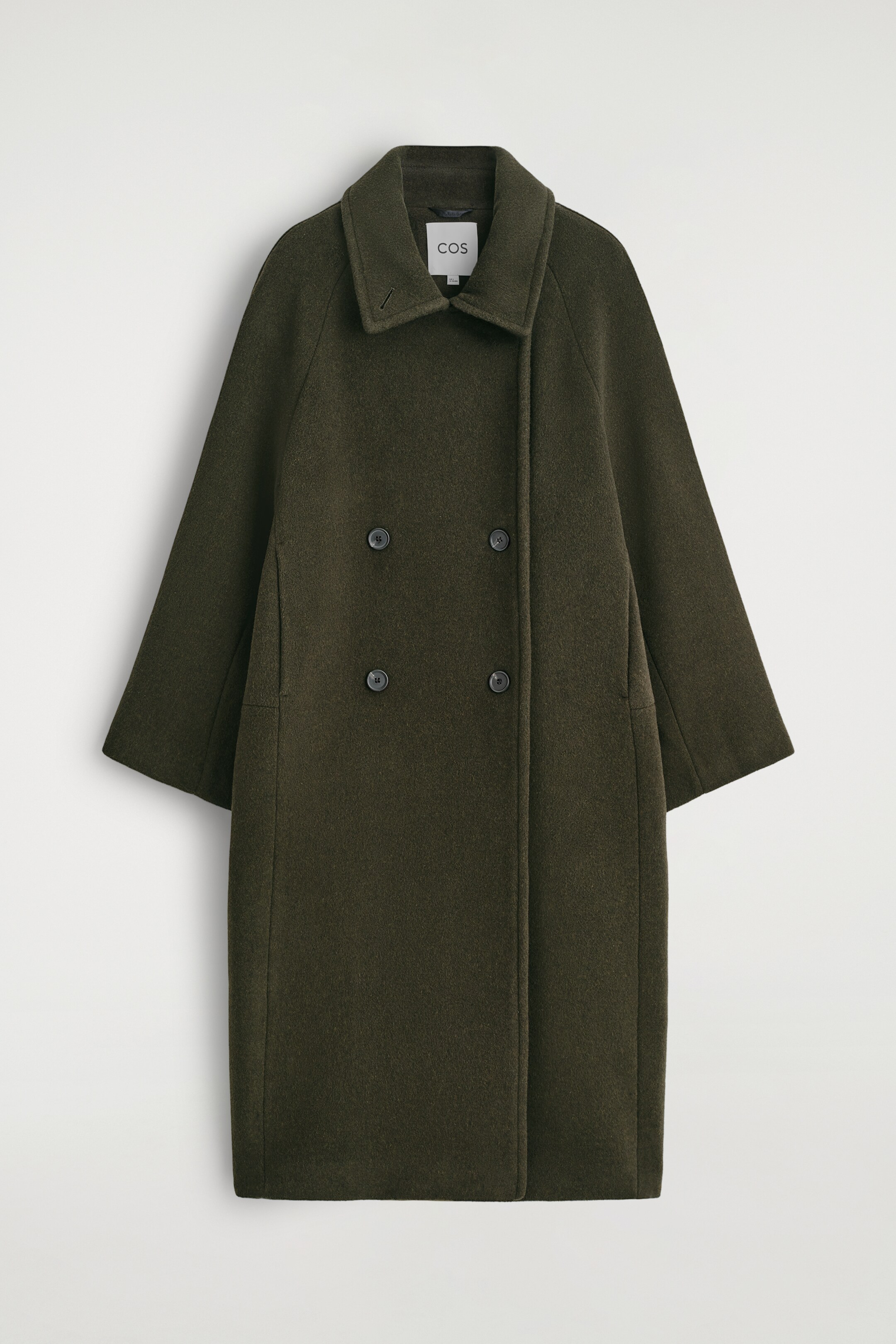 Ingrandisci l'immagine: Un cappotto doppiopetto in misto lana verde oliva scuro viene presentato FRONT. Presenta una silhouette oversize e lunga con maniche raglan e un colletto in piedi. Quattro bottoni scuri chiudono il davanti e due tasche a fessura verticali sono visibili sui lati.