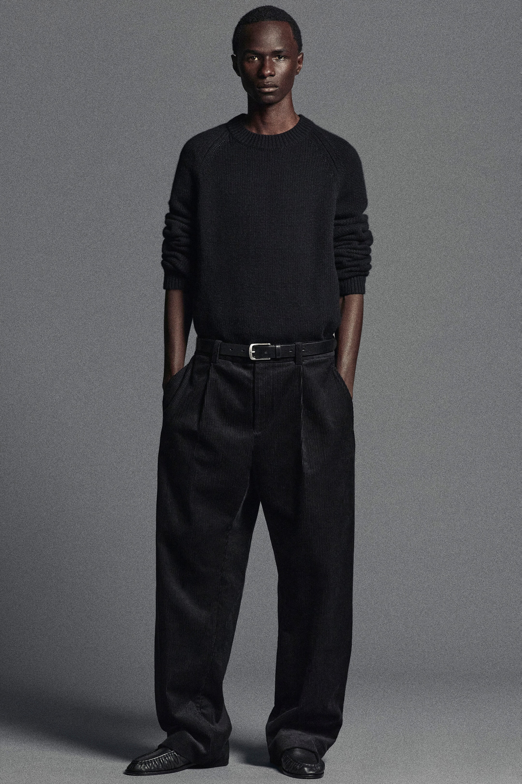 A black chunky cashmere jumper is facing forwards, featuring a ribbed crew neck, raglan sleeves, and ribbed cuffs pushed up the forearms. The jumper is tucked into dark, wide-leg trousers with a belt, highlighting its soft, substantial knit texture and relaxed fit. A black chunky cashmere jumper is facing forwards, featuring a ribbed crew neck, raglan sleeves, and ribbed cuffs pushed up the forearms. The jumper is tucked into dark, wide-leg trousers with a belt, highlighting its soft, substantial knit texture and relaxed fit.