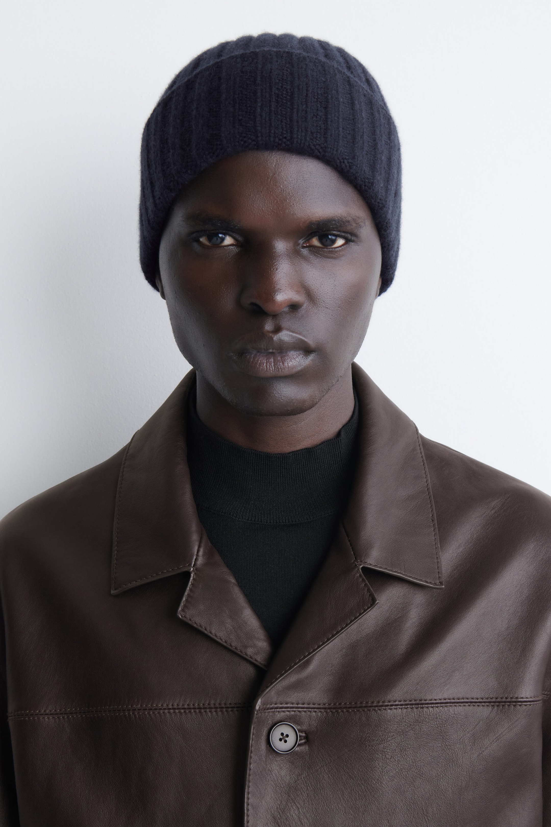A dark navy chunky ribbed cashmere beanie is being worn in a front-facing view, showcasing its snug fit and prominent vertical ribbed-knit texture.