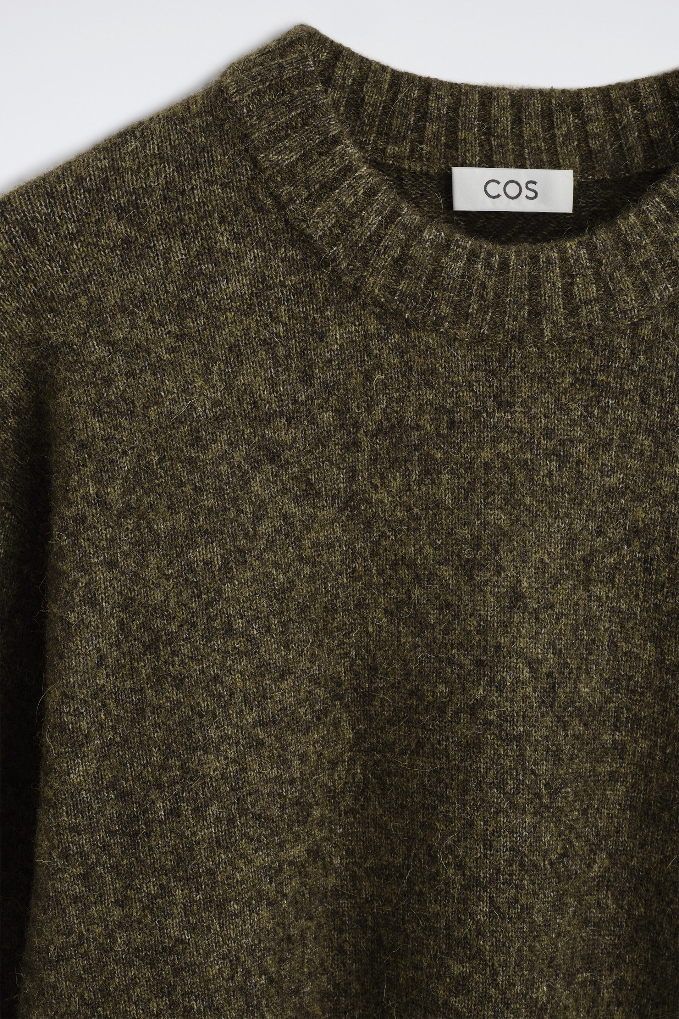 The oversized alpaca-blend crew-neck jumper is shown in a close-up front view, highlighting its textured, melange olive-green knit. The jumper features a thick, ribbed crew neckline and a soft, fuzzy surface. The oversized alpaca-blend crew-neck jumper is shown in a close-up front view, highlighting its textured, melange olive-green knit. The jumper features a thick, ribbed crew neckline and a soft, fuzzy surface.