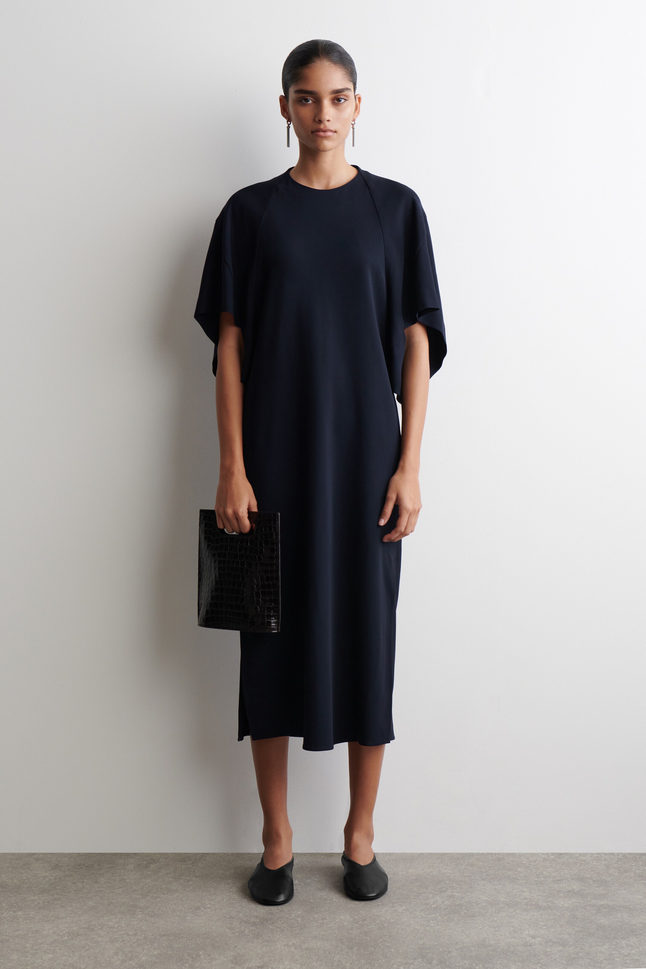 Agrandir l'image: Une robe midi bleu marine est présentée de face, avec un col rond, des manches dolman larges et fluides, et une coupe ample et droite qui s'étend jusqu'à une longueur midi.