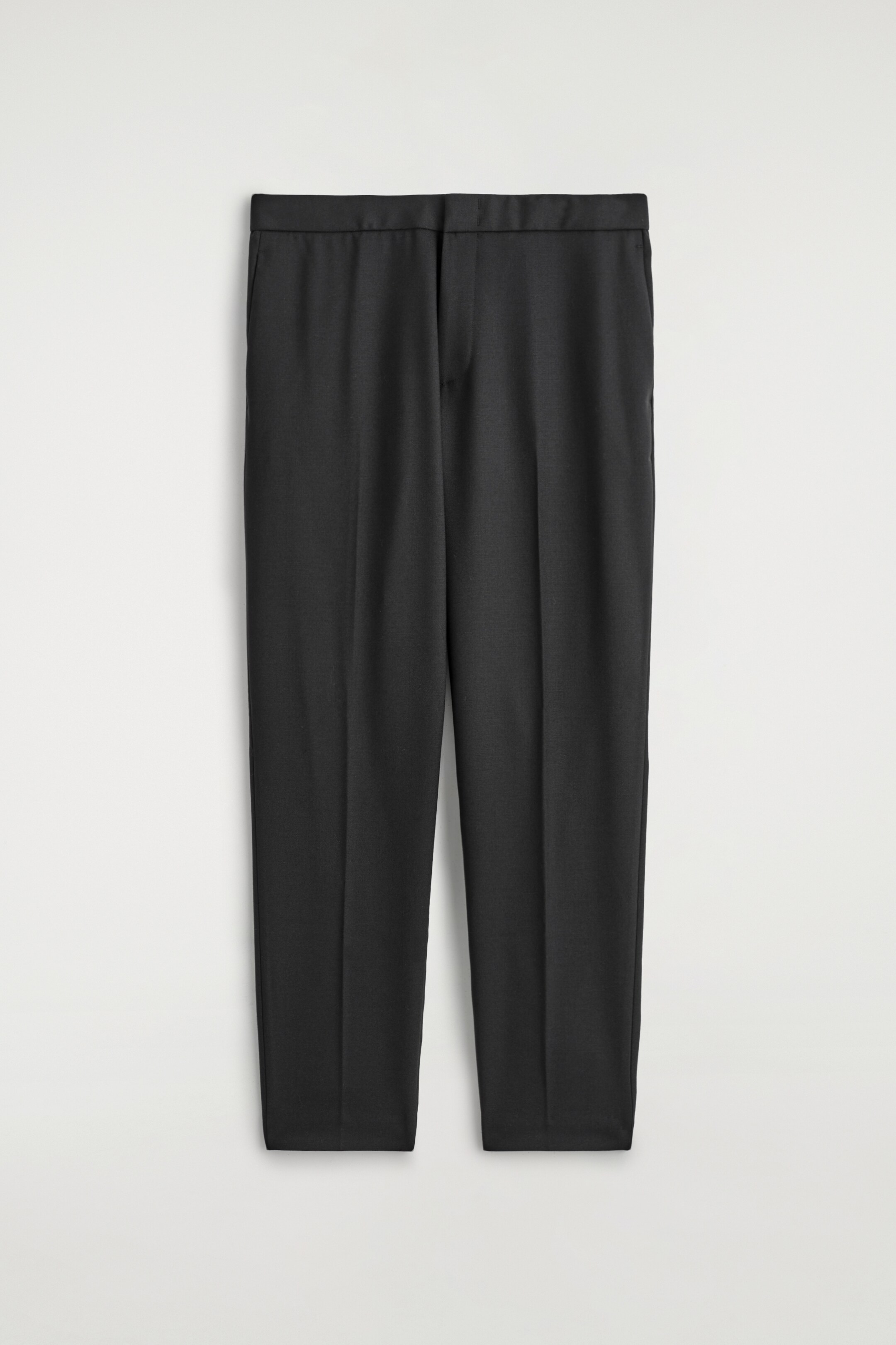 Visualizza immagine più grande: Un paio di pantaloni skinny-fit blu navy sono esposti dalla parte ANTERIORE, mostrando una cintura semplice, una chiusura a gancio, barra e zip, e tasche laterali. Pieghe sono visibili lungo la parte anteriore di ciascuna gamba.