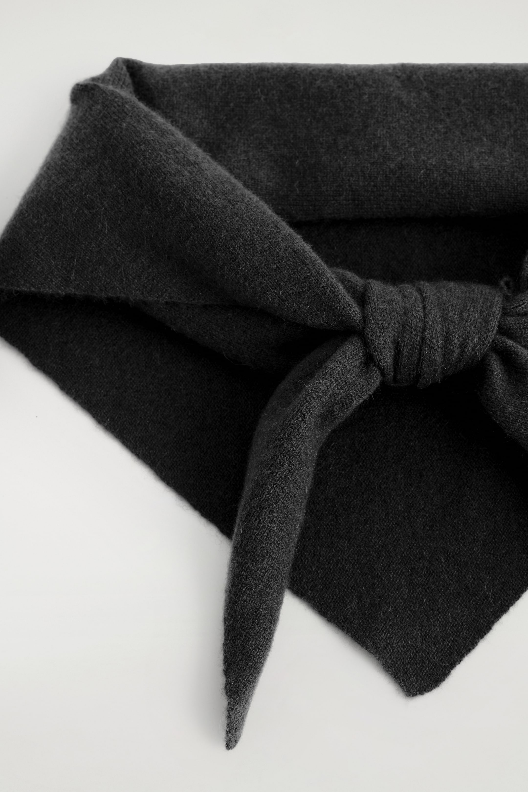 Visualizza immagine più grande: Un foulard a maglia grigio scuro presenta una superficie morbida e strutturata, annodato sul davanti con un'estremità appuntita che si estende verso il basso.
