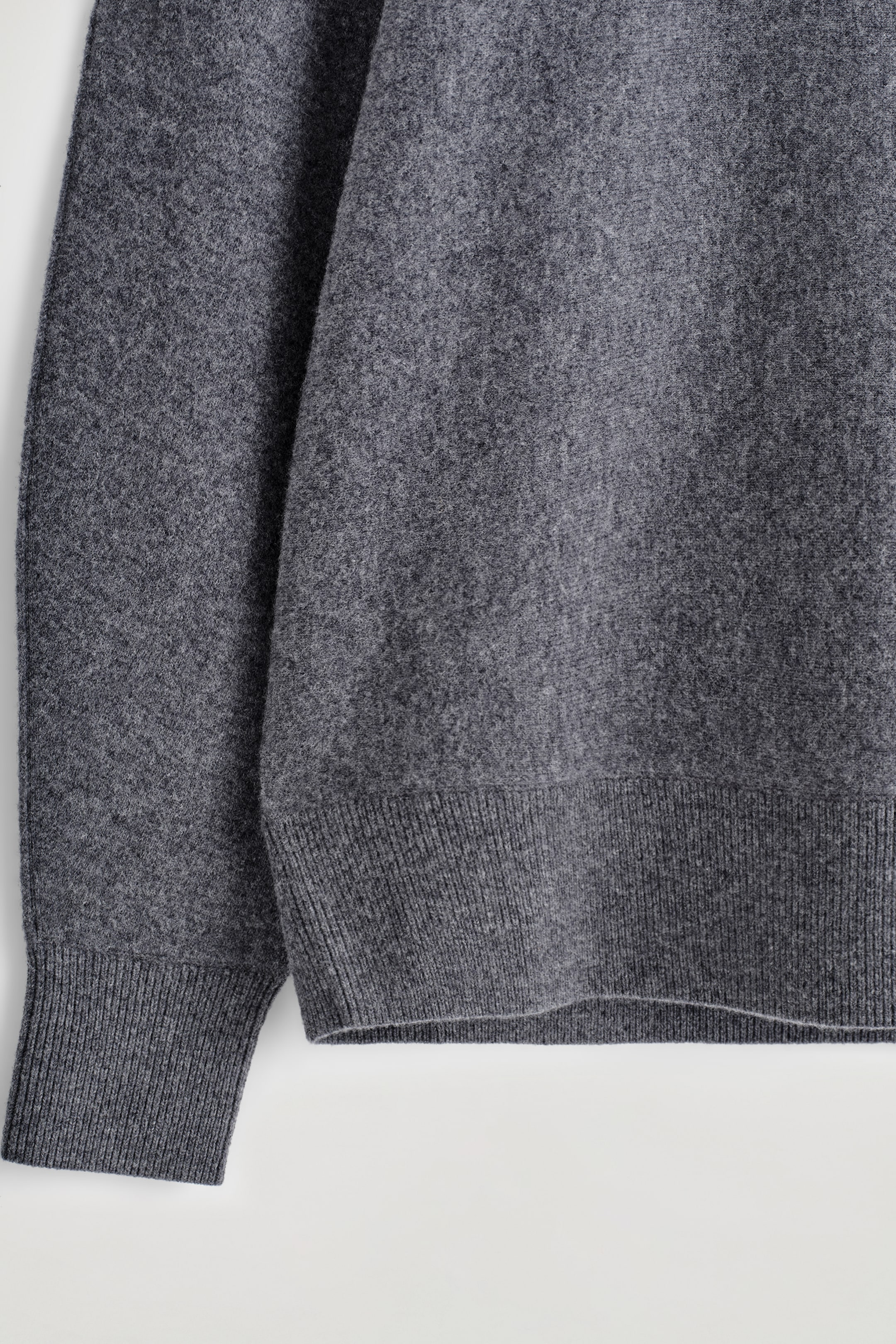 Grösseres Bild ansehen: Ein dunkelgrauer Pullover wird gezeigt, der einen glatt gestrickten Körper und Ärmel mit einem gerippten Saum und einer gerippten Manschette aufweist.
