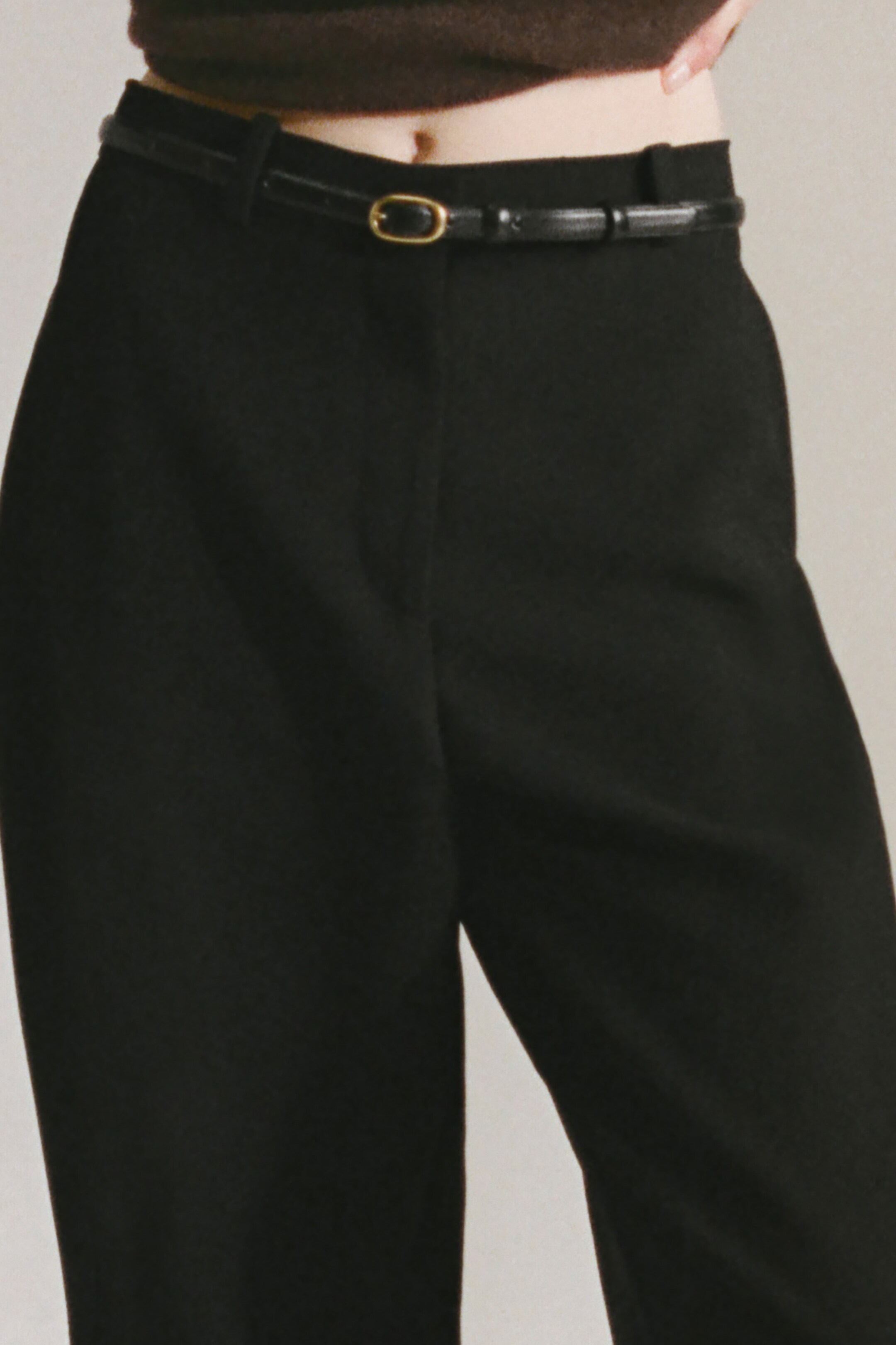 Größeres Bild anzeigen: Mole-Ton-Hosen zeichnen sich durch einen Barrel-Leg-Schnitt und nach vorne gerichtete Nähte aus, die eine abgerundete Silhouette betonen. Ein schmaler schwarzer Ledergürtel mit einer goldfarbenen ovalen Schnalle wird durch die Gürtelschlaufen der Hose getragen und präsentiert die Vorderansicht.