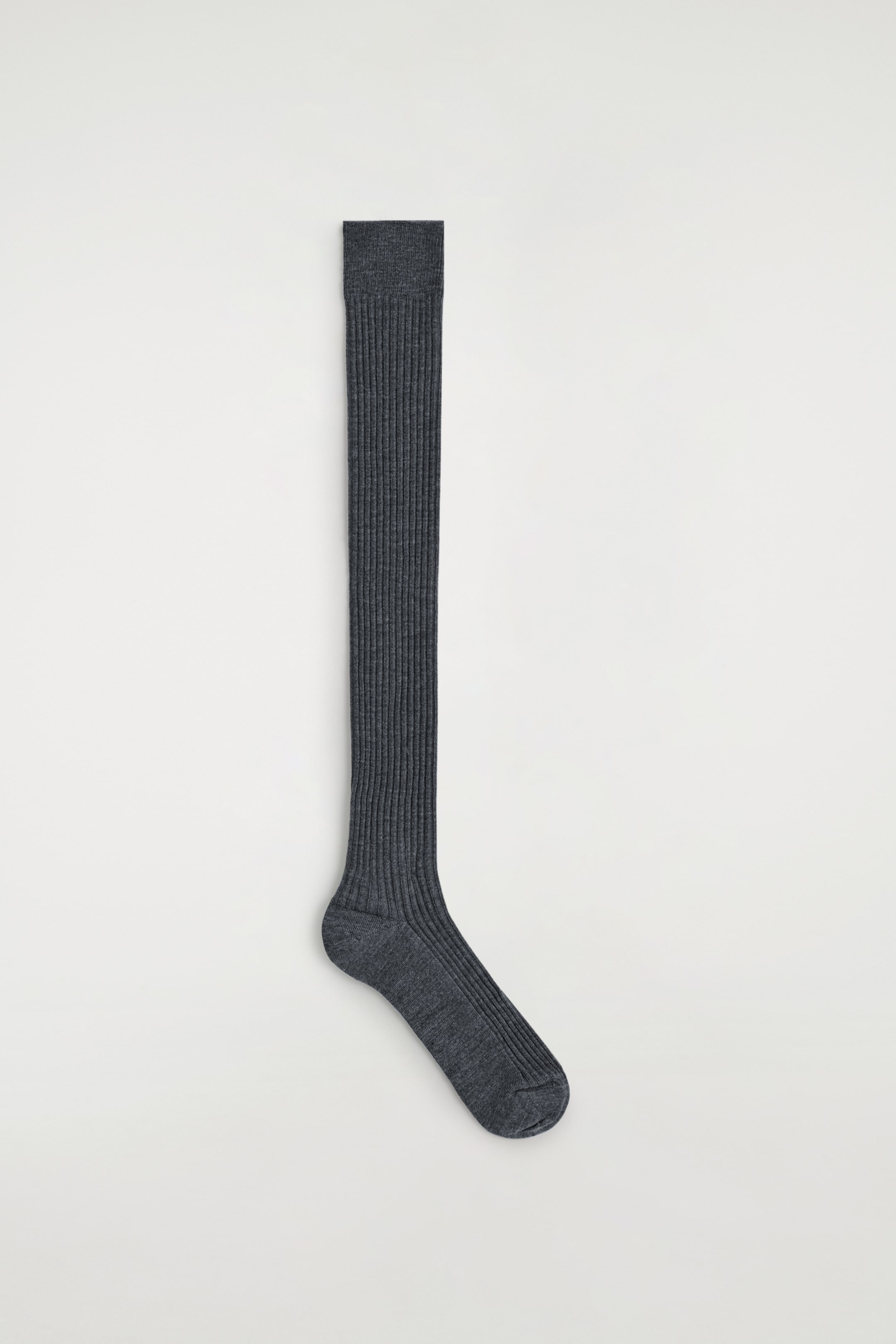 Agrandir l'image: Une chaussette gris foncé montant jusqu'au genou est affichée verticalement, avec une texture côtelée uniforme le long de sa jambe et de son pied, et une bande lisse en haut du poignet.