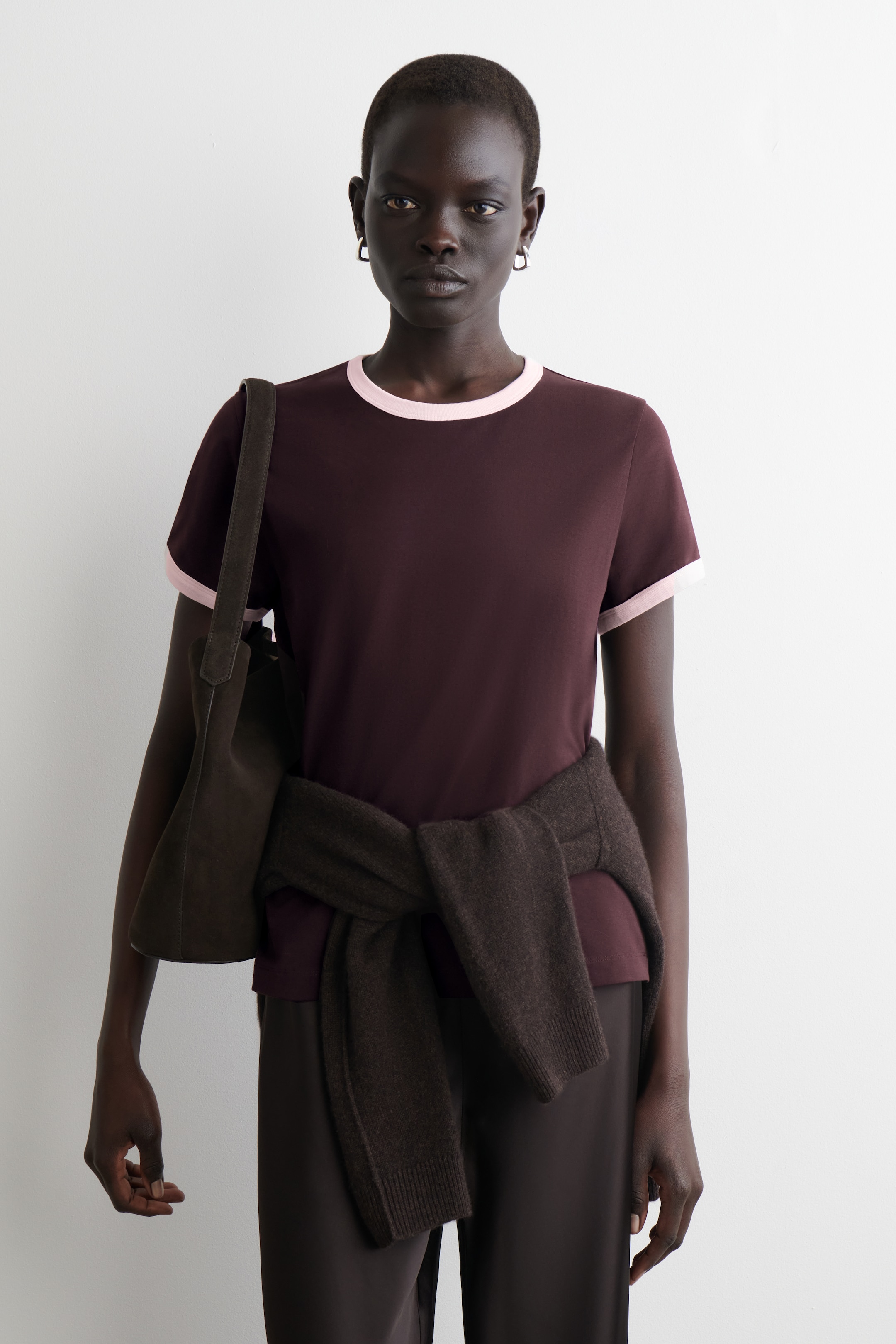 Agrandir l'image: Un T-shirt à liseré est présenté de face, avec un corps principal brun-rouge foncé et des bordures rose clair. Il comprend un col rond et des manches courtes, ajustées de manière étroite au corps.
