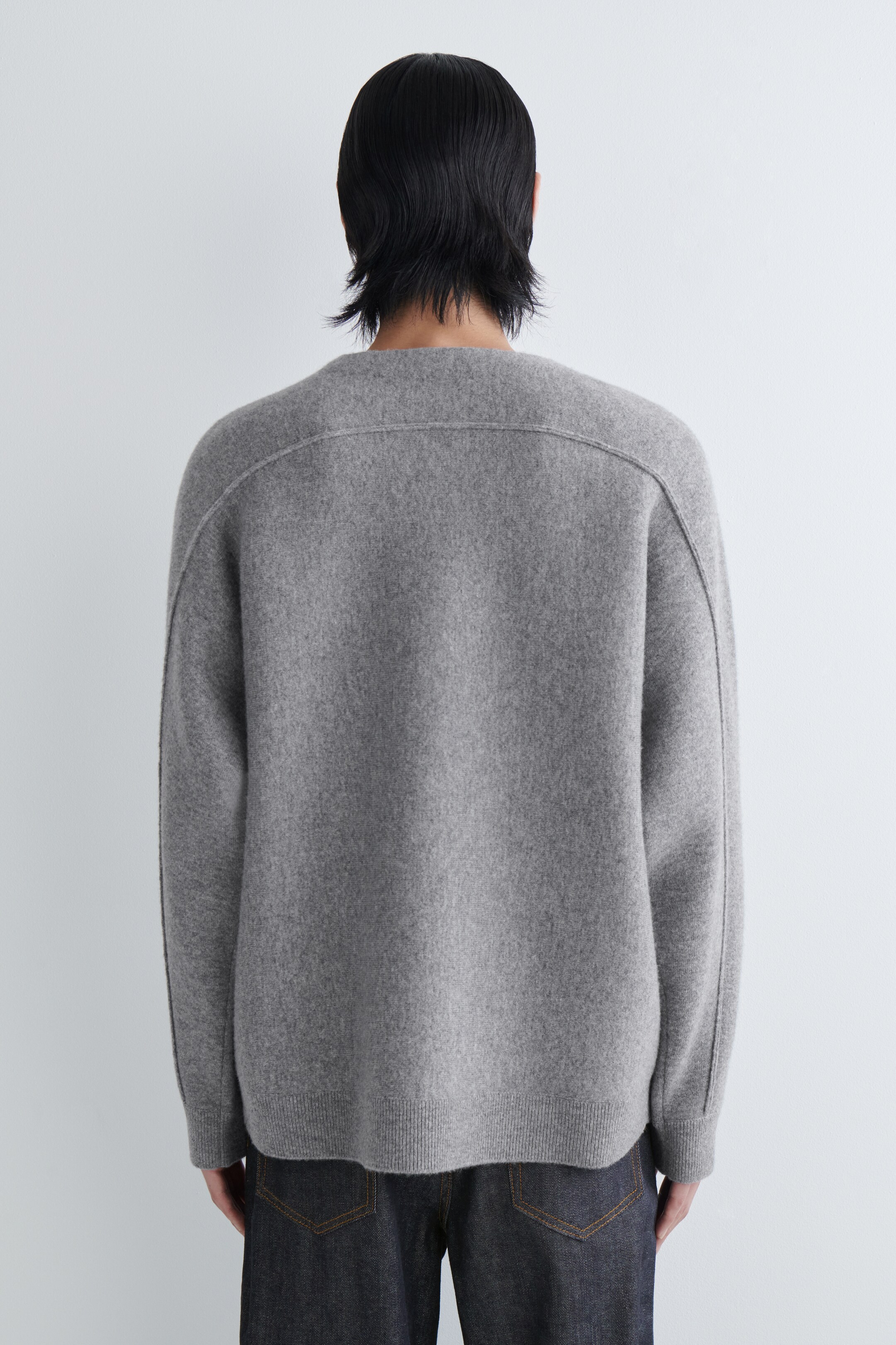 Agrandir l'image: Un pull gris à col rond est présenté de dos, avec une coupe décontractée et des épaules tombantes. Il présente des coutures proéminentes qui traversent le haut du dos et descendent le long des manches, et est fini avec un ourlet côtelé.