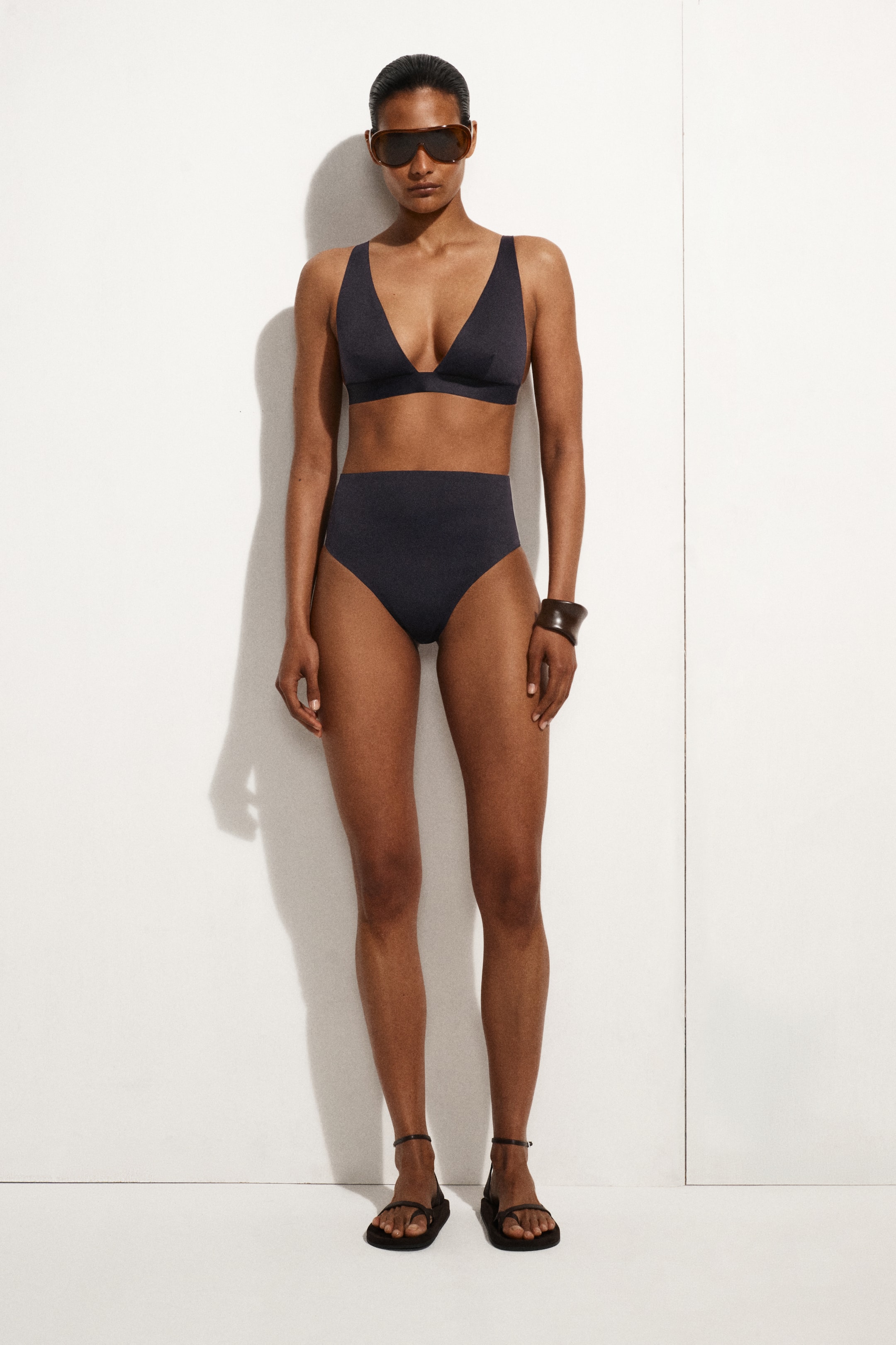 Visa större bild: Mörkgrå bikiniunderdel med hög midja och hög skärning vid benen med rena kanter bärs av modellen, som också har på sig en matchande bikinitopp.