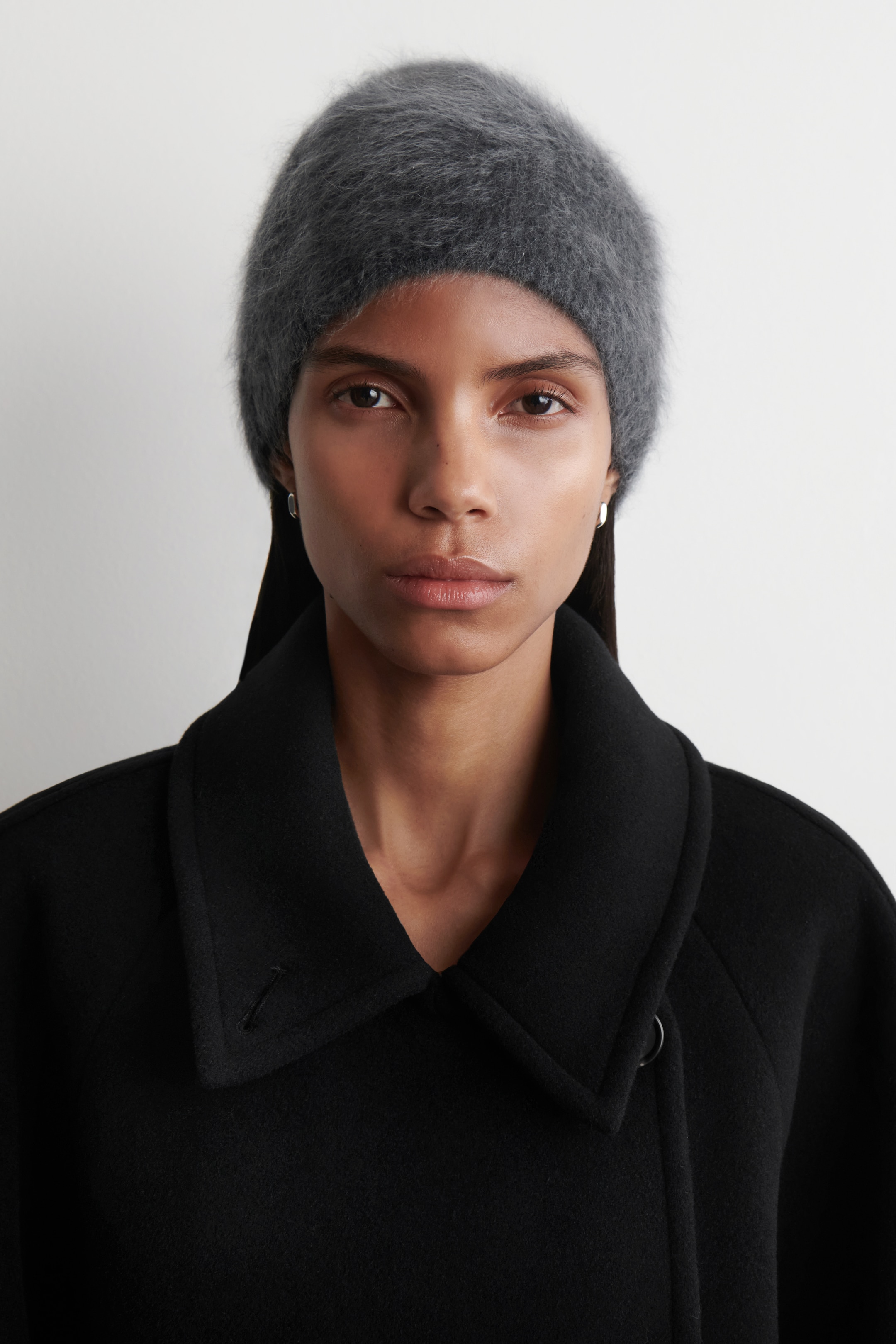 Agrandir l'image: Un bonnet en charbon est présenté de face, exhibant une texture visiblement brossée et duveteuse. Le bonnet s'ajuste parfaitement autour de la tête, avec son matériau doux semblant couvrir les oreilles.