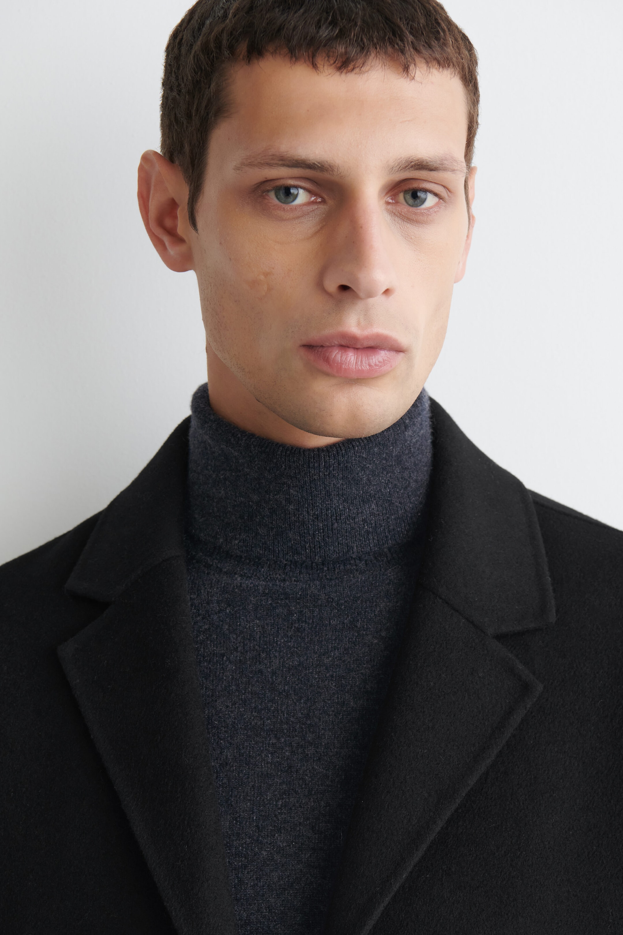 Un pull à col roulé en cachemire gris foncé est mis en avant dans un gros plan de la partie supérieure, mettant en valeur son col ajusté et montant. Le pull est porté sous un manteau noir structuré à revers crantés, soulignant sa texture douce en maille fine. Un pull à col roulé en cachemire gris foncé est mis en avant dans un gros plan de la partie supérieure, mettant en valeur son col ajusté et montant. Le pull est porté sous un manteau noir structuré à revers crantés, soulignant sa texture douce en maille fine.