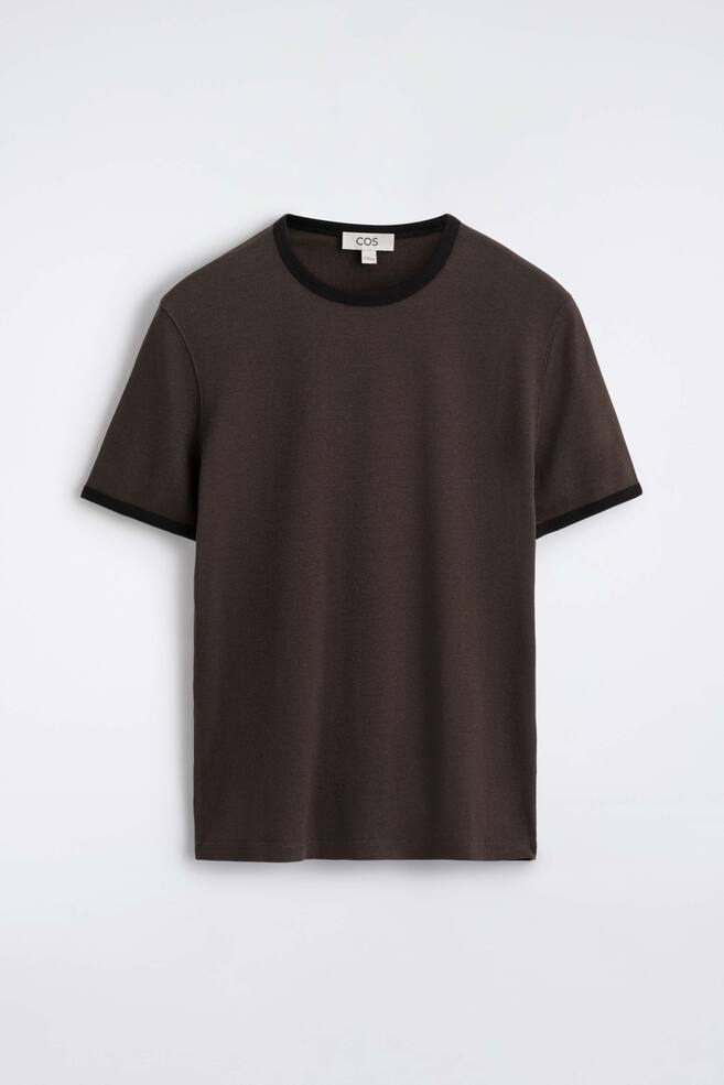 Ein schmal geschnittenes, geripptes Baumwoll-T-Shirt ist von vorn zu sehen und zeigt ein dunkelbraunes Feinstrick-Rippgewebe mit einem kontrastierenden schwarzen Rundhalsausschnitt und passenden schwarzen AbschlÃ¼ssen an den kurzen ÃrmelbÃ¼ndchen. - 1