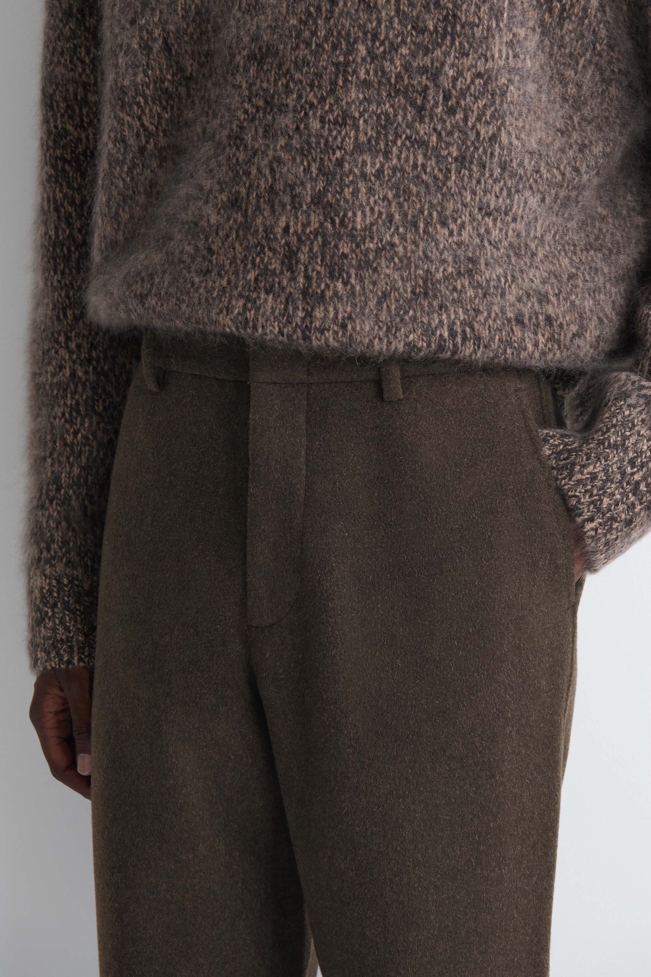 The model is wearing dark brown double-faced wool-blend straight-leg pants, resting one hand in the side pocket. The pants feature belt loops and a clean concealed front closure, styled with a fuzzy melange brown knit sweater. The model is wearing dark brown double-faced wool-blend straight-leg pants, resting one hand in the side pocket. The pants feature belt loops and a clean concealed front closure, styled with a fuzzy melange brown knit sweater.
