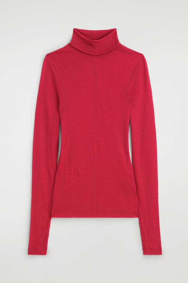 Uma camisola de gola alta em lÃ£ merino, em vermelho vibrante, estÃ¡ virada de frente, destacando uma silhueta slim fit com gola de gola alta dobrada. As mangas compridas descem, com pequenas aberturas para os polegares visÃ­veis nos punhos. - 1