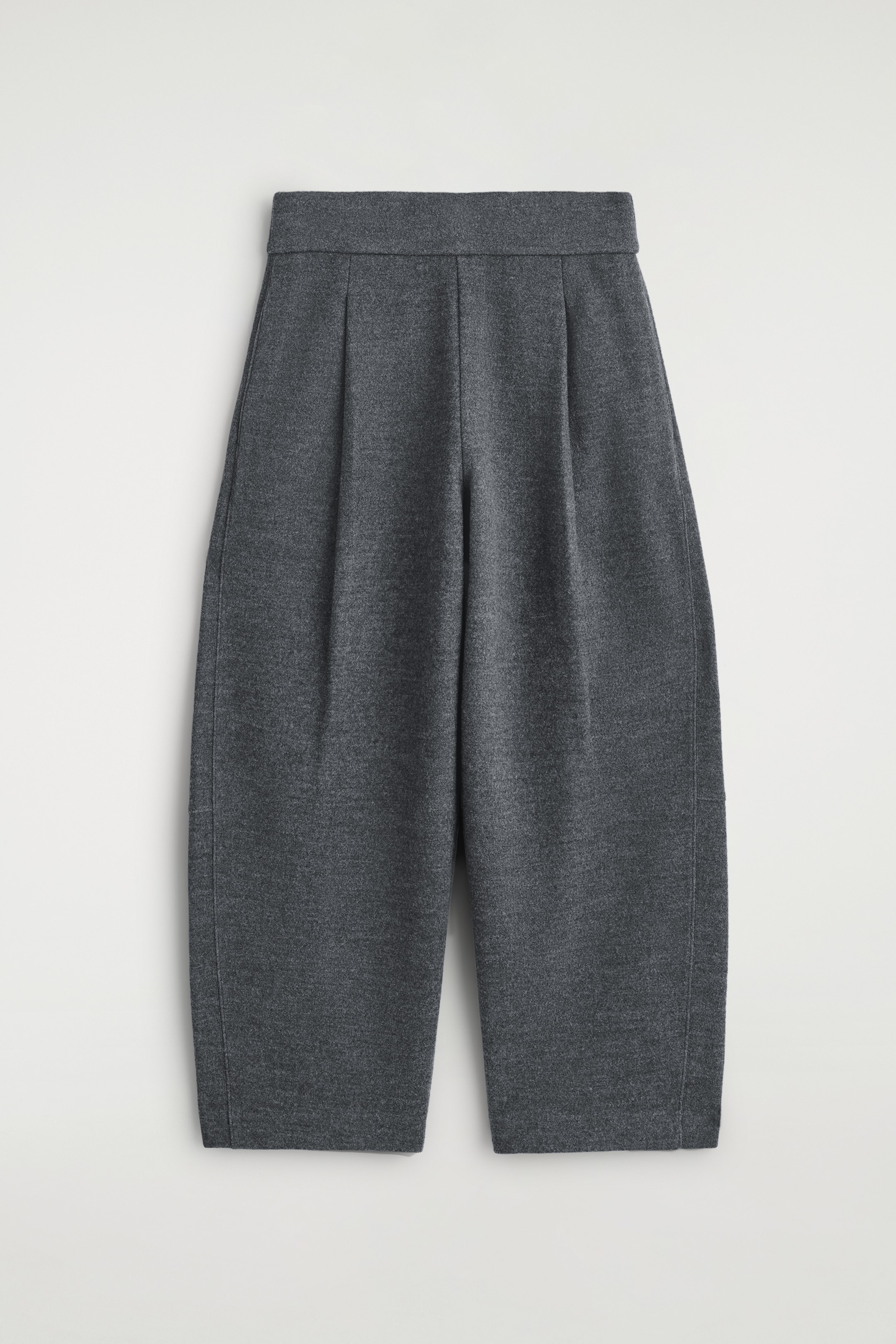 View larger image: Dark gray trousers are being displayed from the FRONT, featuring a relaxed, curved barrel-leg silhouette. They are designed with an elasticated waistband and prominent front pleats, showcasing a soft, textured fabric.