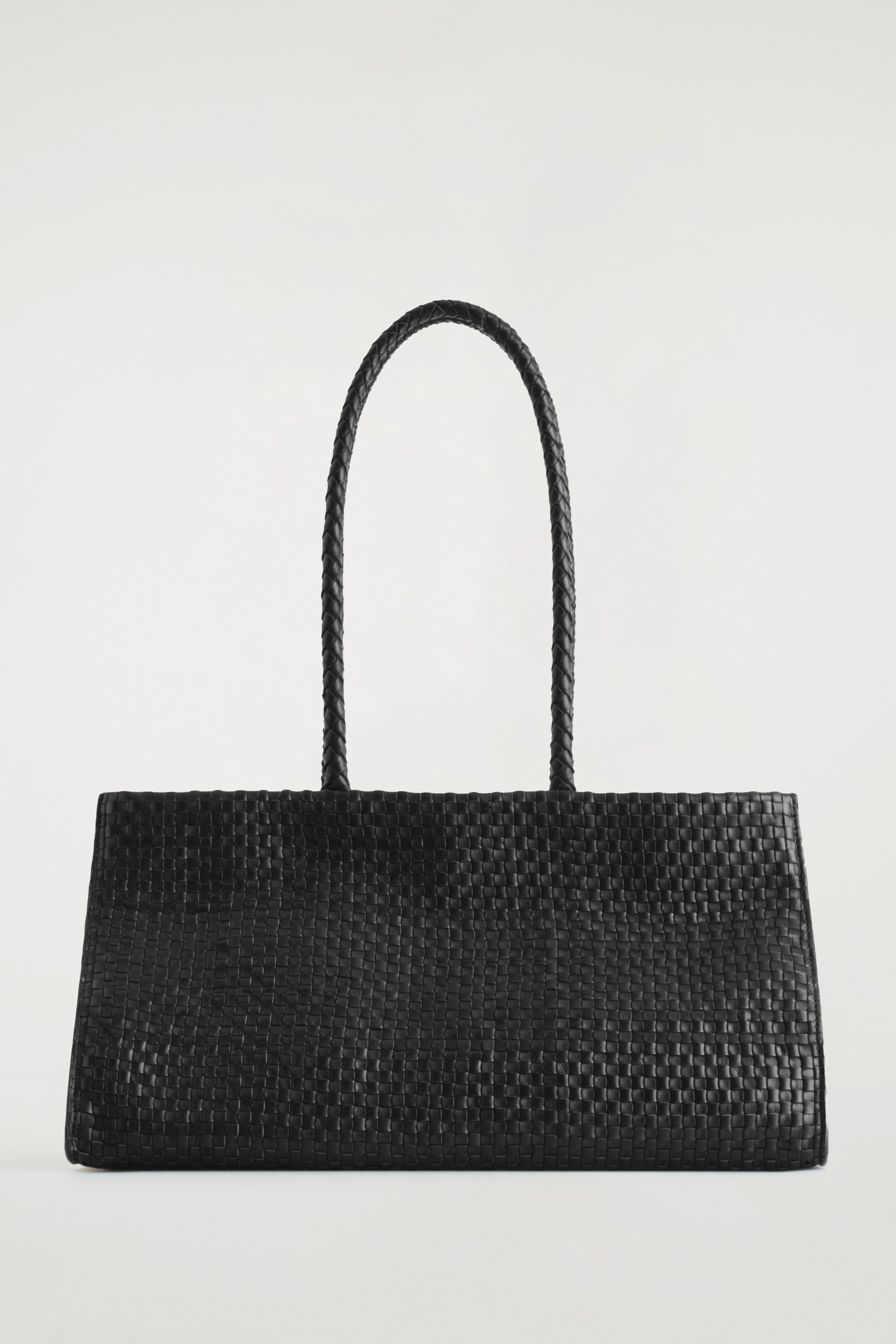 Ver imagen más grande: Se presenta un bolso tote de cuero negro desde el FRENTE, con un diseño de silueta de este a oeste. Su superficie está intrincadamente trenzada a mano y muestra dos correas de hombro largas y trenzadas.