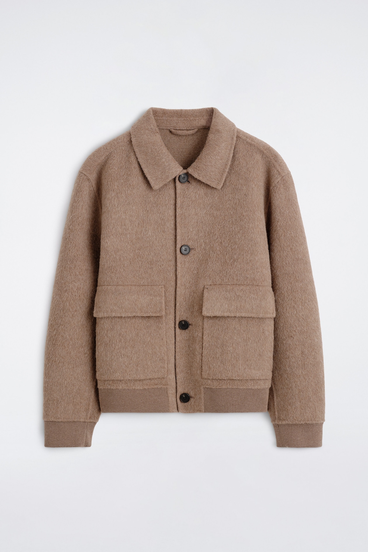The double-faced blouson jacket is shown from the front, showcasing a textured taupe-brown wool fabric with a classic pointed collar and a dark button-front closure. It features two large front patch pockets with flaps, dropped shoulders, and ribbed knit detailing at the cuffs and hem.