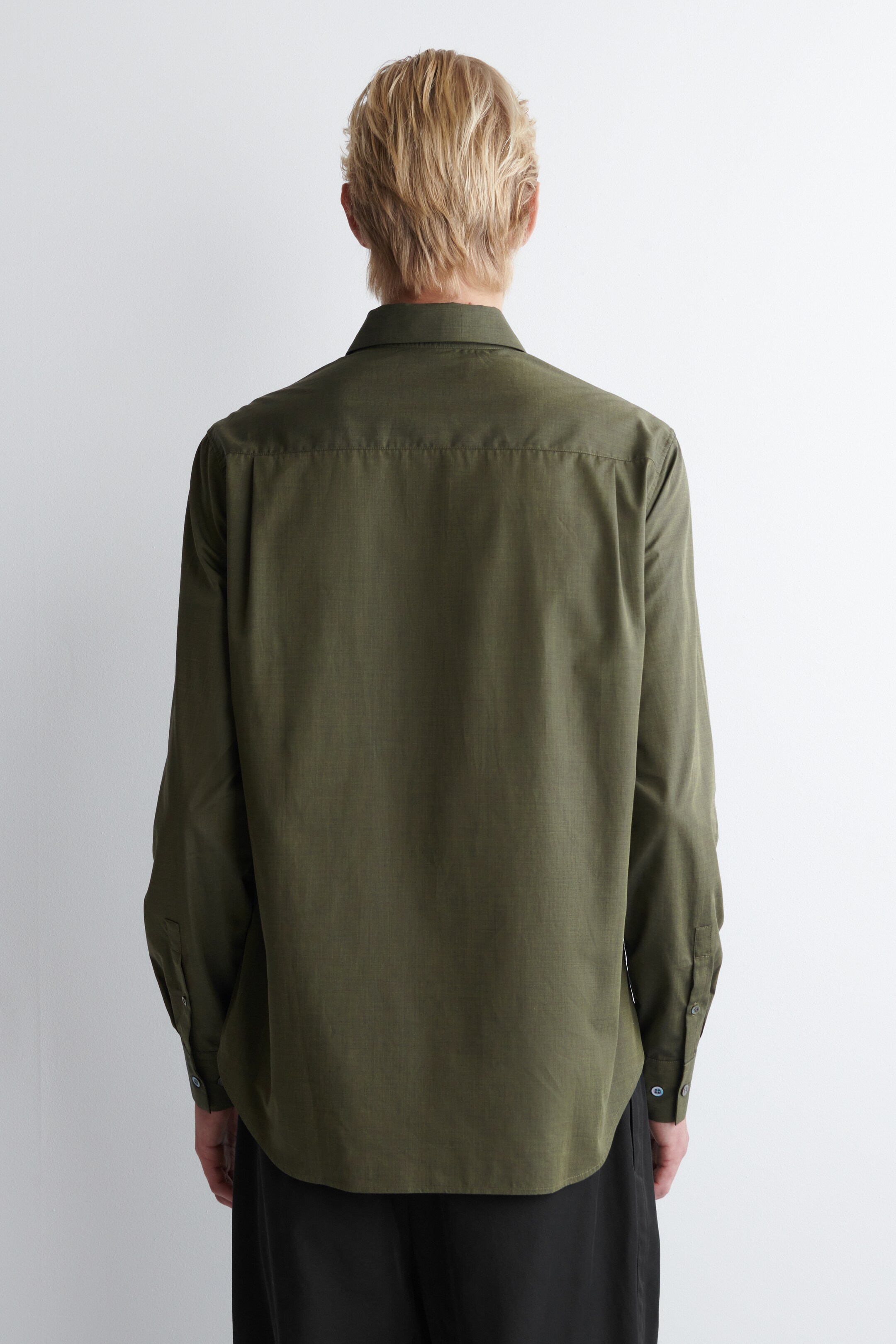 Ver imagen más grande: La camisa de manga larga de color verde oliva se muestra desde atrás, presentando un cuello clásico y un canesú trasero horizontal. Está presentando mangas largas con puños de barril con botones, un dobladillo curvado y un tejido texturizado.