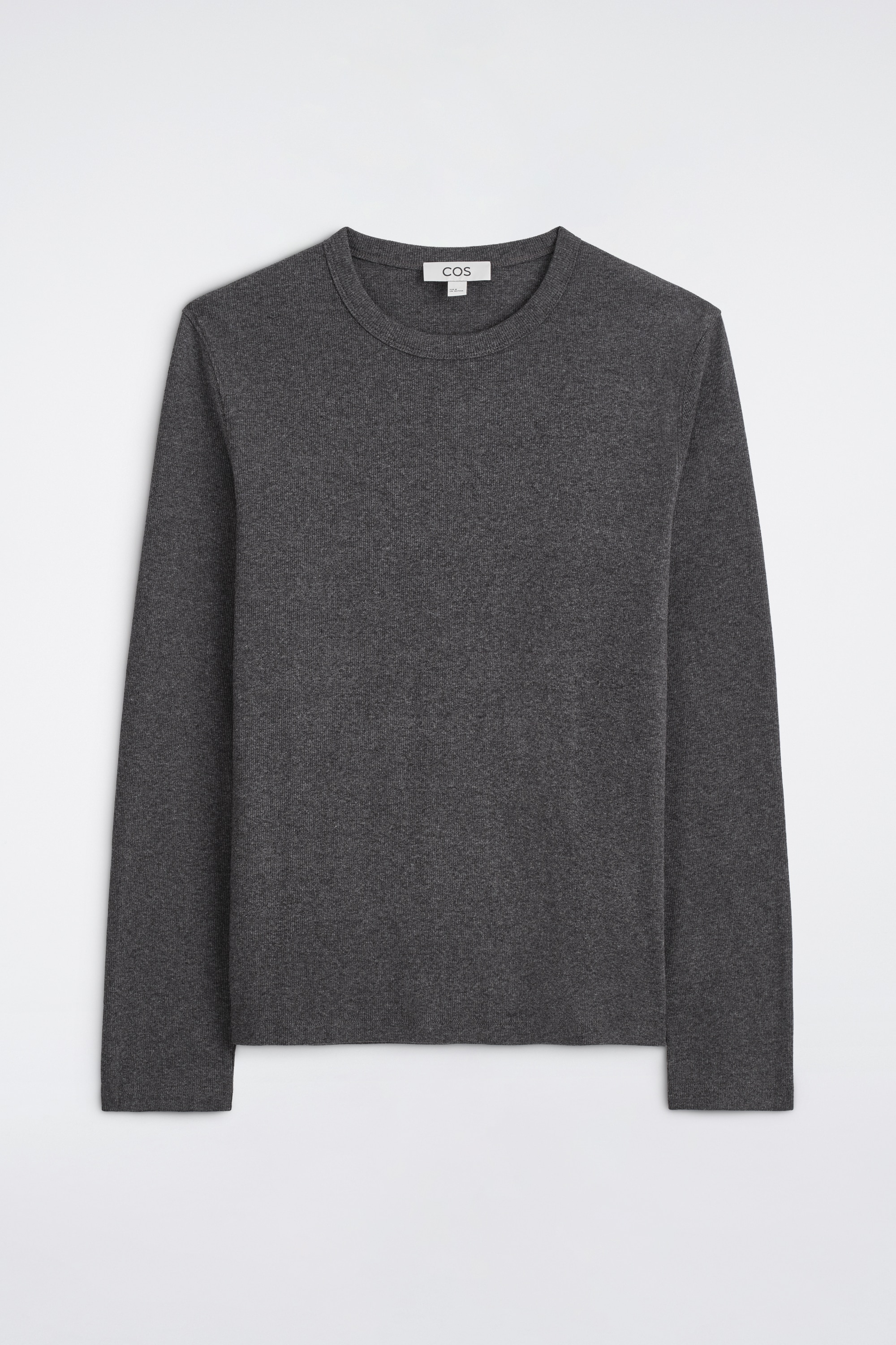 A dark grey, long-sleeved crew neck top is shown from the front, showcasing a slim-fit silhouette and a fine-knit texture. The top is worn tucked into dark pleated trousers secured with a black belt, highlighting its clean, close-fitting design.
