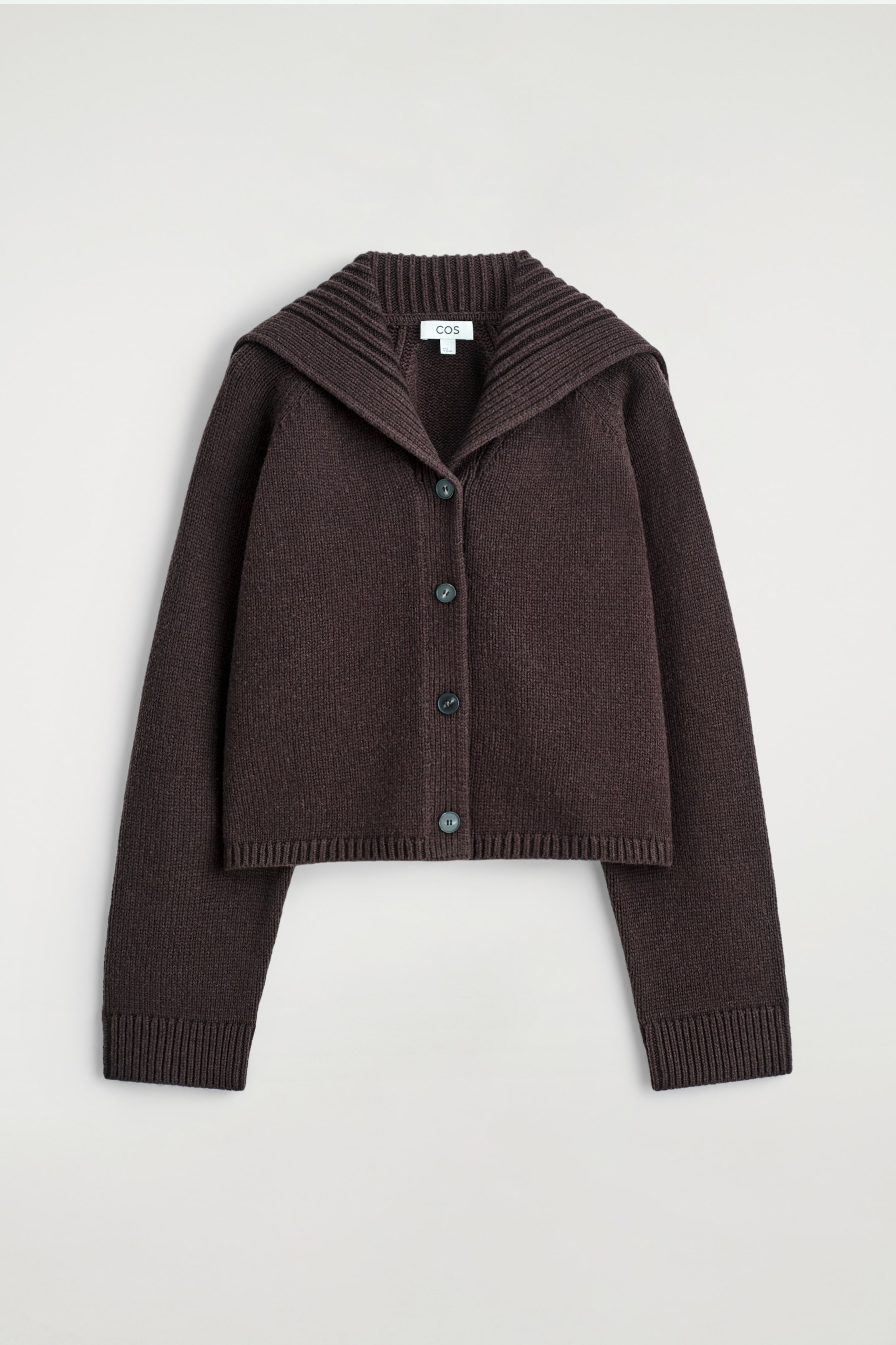 Größeres Bild ansehen: Eine dunkelbraune, kastenförmige Strickjacke wird von vorne präsentiert, mit einem breiten, gerippten Matrosenkragen, der über die Schultern fällt. Sie ist mit einem Knopfverschluss vorne gestaltet, der vier dunkelgrüne Knöpfe zeigt, und hat lange Ärmel, die in gerippten Bündchen und einem gerippten Saum enden.