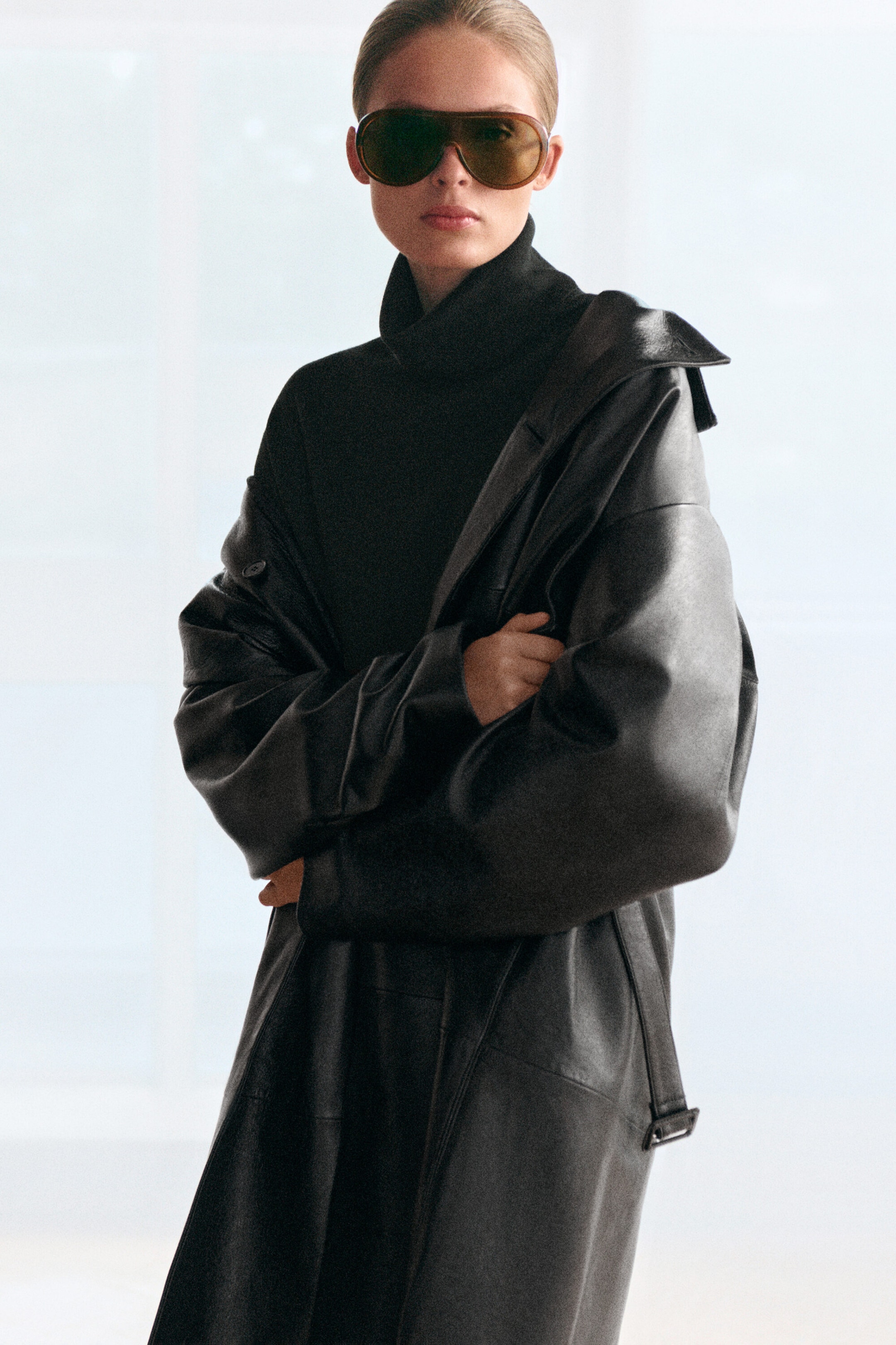 A black merino wool turtleneck sweater is worn facing forward, featuring a high, folded turtleneck collar. The sweater is layered under a loose-fitting black leather coat draped over the shoulders, showcasing the fine-knit texture at the neck and chest. A black merino wool turtleneck sweater is worn facing forward, featuring a high, folded turtleneck collar. The sweater is layered under a loose-fitting black leather coat draped over the shoulders, showcasing the fine-knit texture at the neck and chest.