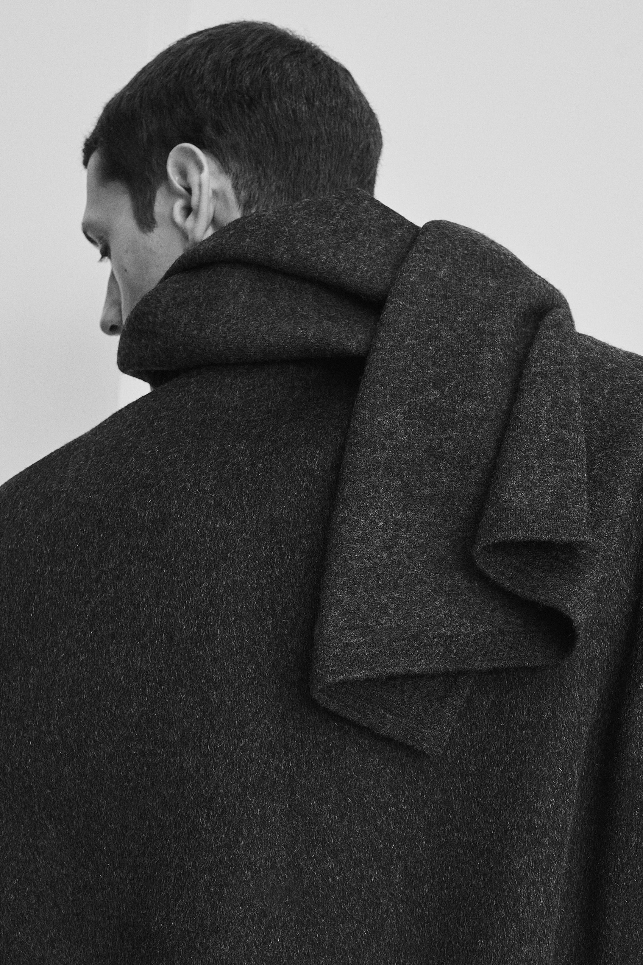 En mörktonad halsduk i kokt ull bärs draperad över axeln på en matchande okonstruerad blazer i ullblandning, visad ur en bakifrån-vinkel. Båda plaggen visar upp ett tätt, strukturerat tyg i kokt ull med en mjuk, matt finish. En mörktonad halsduk i kokt ull bärs draperad över axeln på en matchande okonstruerad blazer i ullblandning, visad ur en bakifrån-vinkel. Båda plaggen visar upp ett tätt, strukturerat tyg i kokt ull med en mjuk, matt finish.