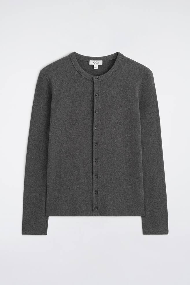 Diese schmal geschnittene, gerippte Baumwollstrickjacke ist von vorne in einem dunklen Anthrazitgrau zu sehen und verfÃ¼gt Ã¼ber einen Rundhalsausschnitt sowie lange Ãrmel. Das Strickteil zeigt einen vorderen Knopfverschluss mit kleinen, farblich abgestimmten KnÃ¶pfen entlang einer mittigen Knopfleiste und einem sauberen, geraden Saum. - 1