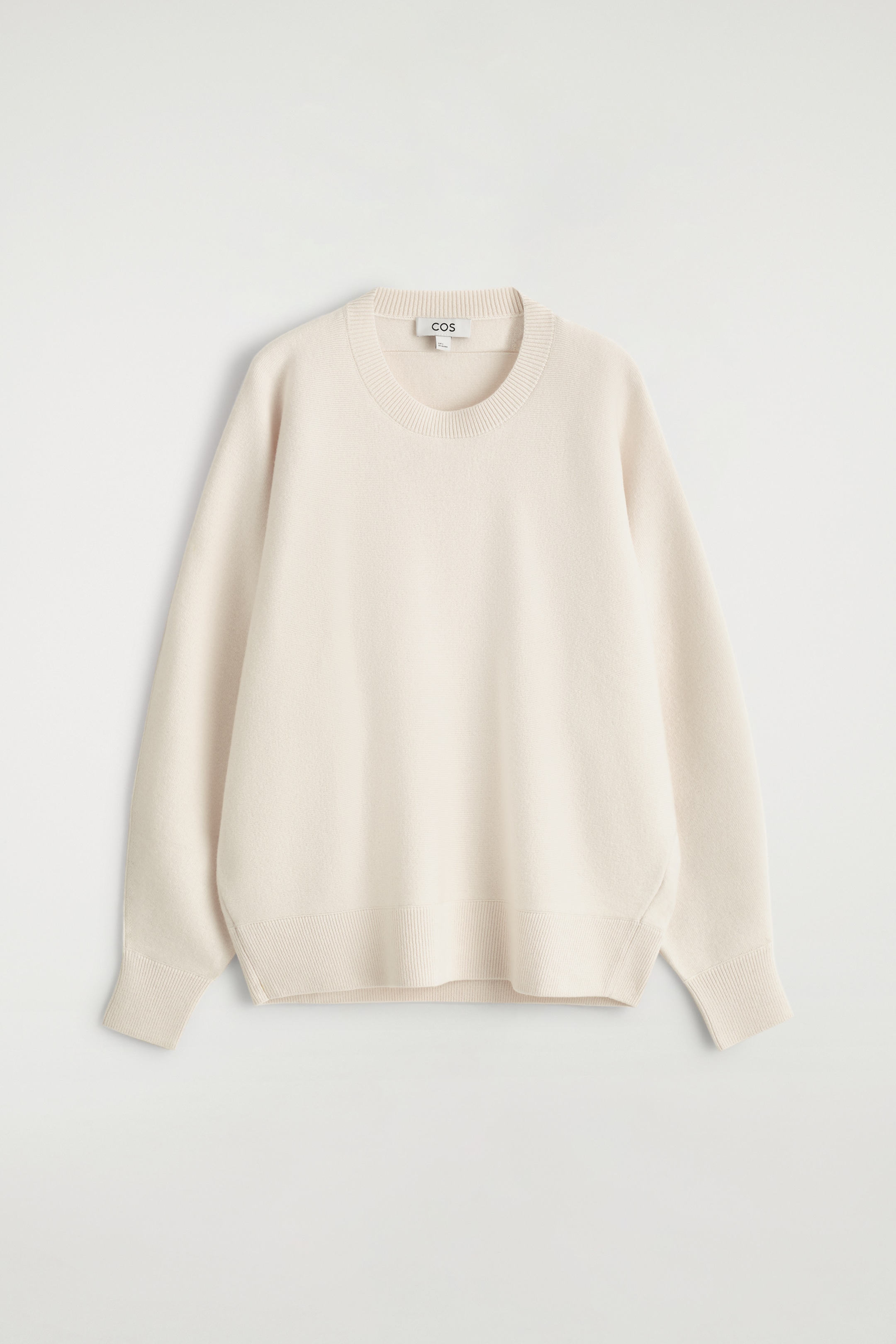 Visualizza immagine più grande: Un maglione a maglia di colore crema chiaro viene presentato FRONTALE, caratterizzato da uno scollo rotondo a costine, maniche lunghe e arrotondate con polsini a costine e un orlo a costine, che contribuiscono al suo silhouette rilassato.