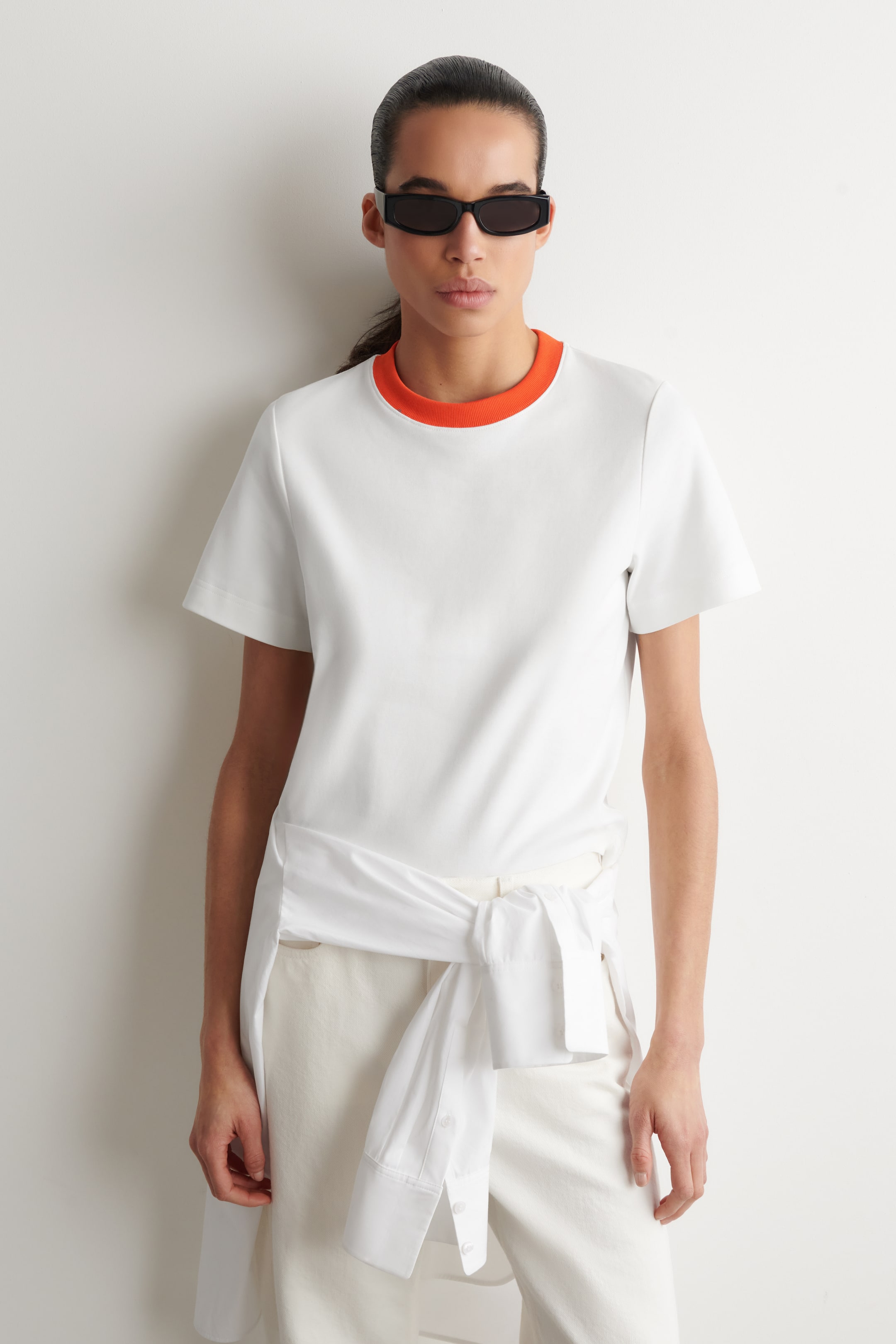 Agrandir l'image: Un t-shirt blanc à manches courtes est présenté de face, avec un col rond côtelé orange.