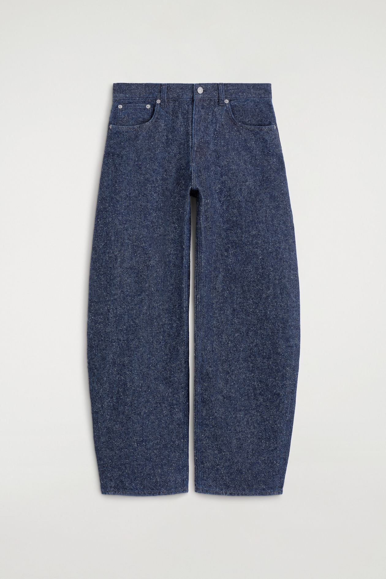 The dark blue jeans feature a wide, barrel-shaped silhouette with a speckled texture, featuring a front button fly closure with a single metal button and two curved front pockets with metal rivets.