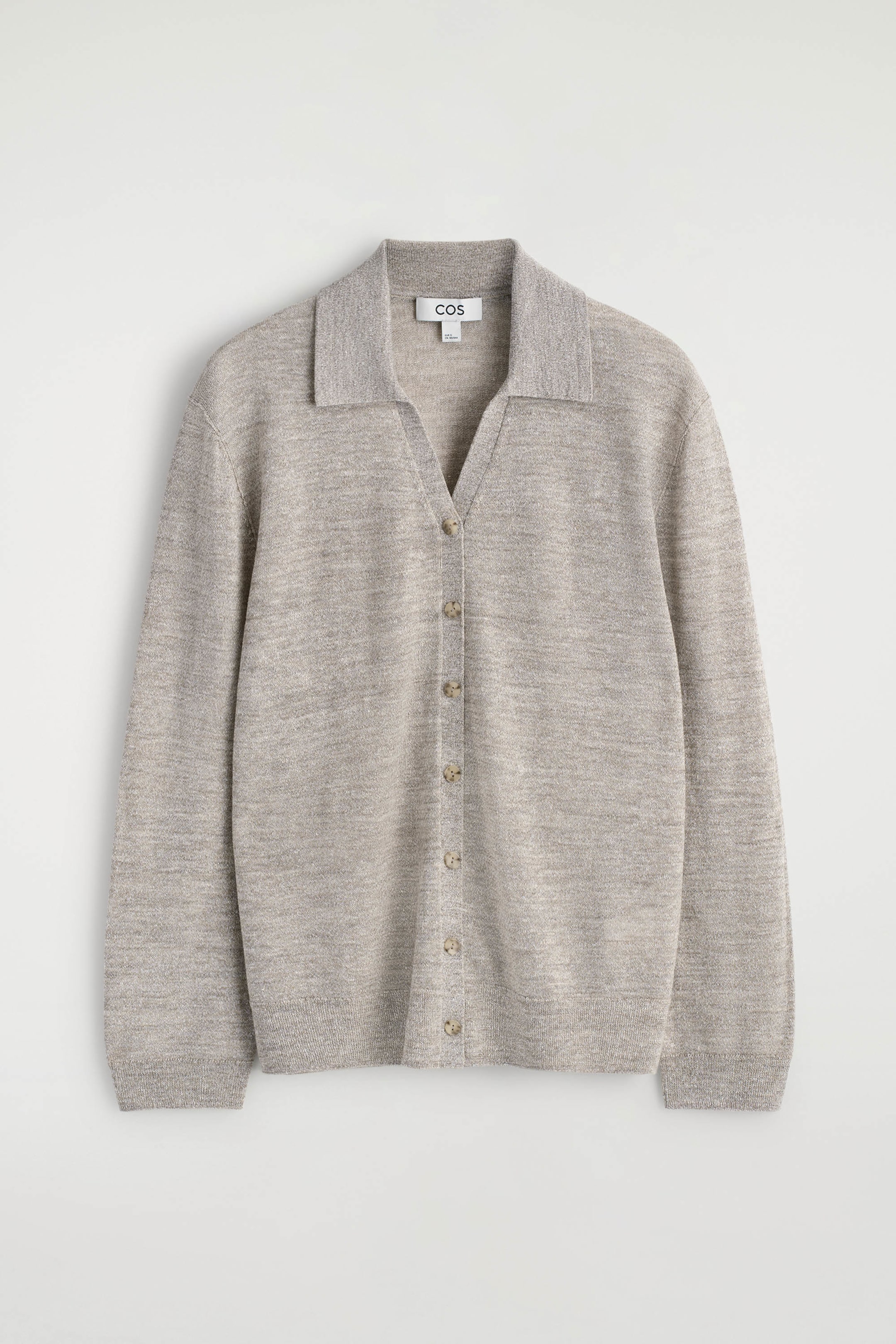 Se større billede: En lysebeige meleret strikket polo-cardigan fremviser sin forside med en spredekrave og en fuld knapstolpe med syv små, runde, lysebrune knapper. Den har lange ærmer med ribstrikkede manchetter og en ribbet kant.